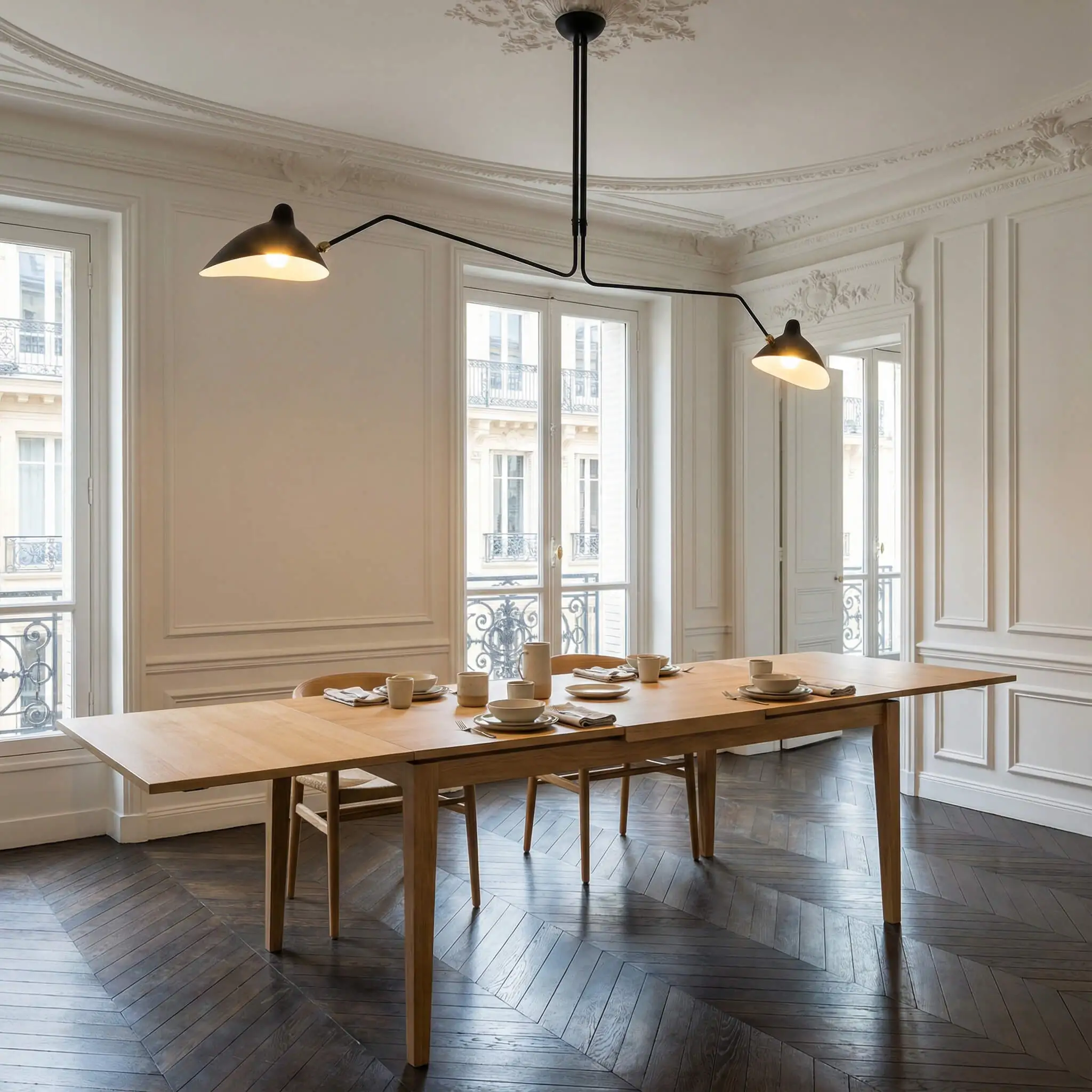 Black swing-arm chandelier with articulated arms extended over a long wood dining table.