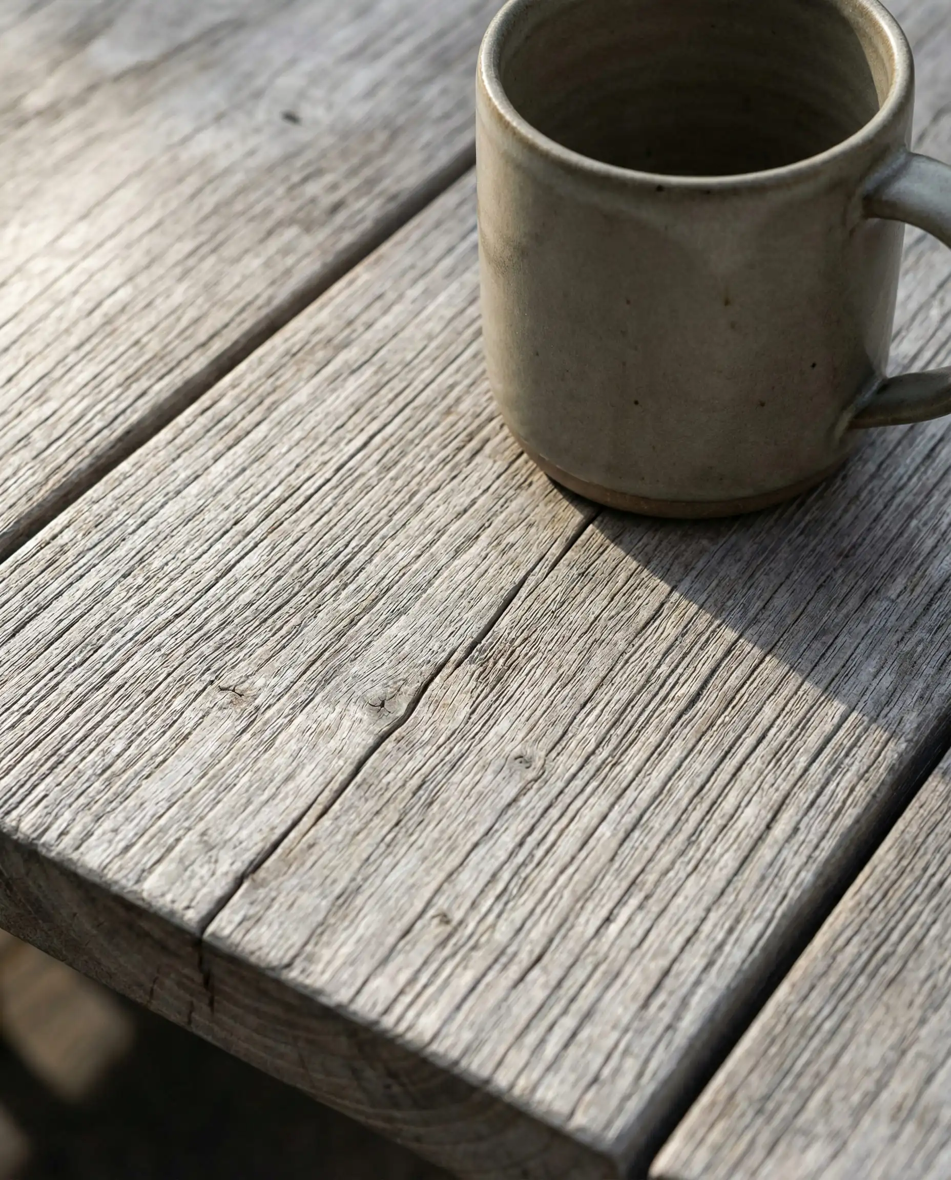 Close-up detail of aged teak wood furniture showing a silver-grey natural patina.