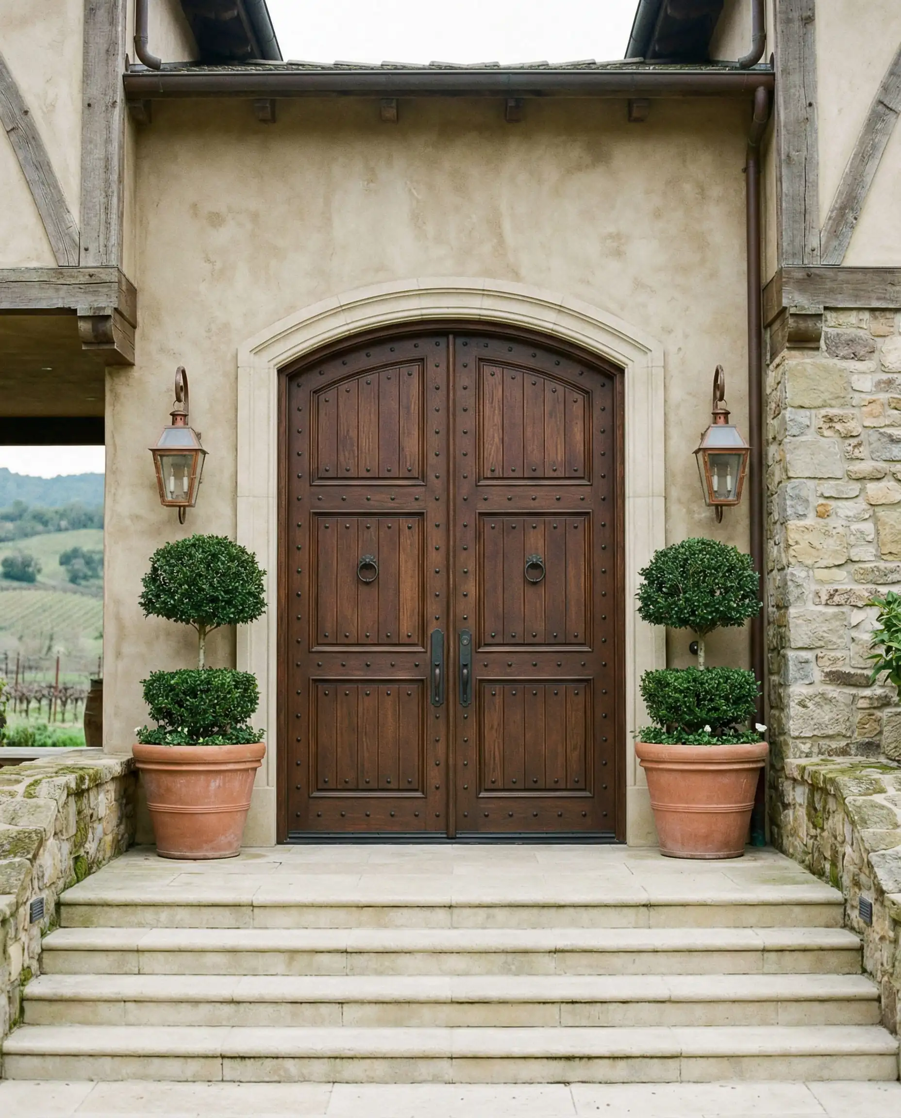 Grand farmhouse entrance with double arched walnut front doors and limestone steps.