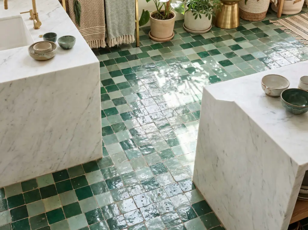 Une cuisine bohÚme chic et dynamique, ornée de carreaux de sol artisanaux émaillés dans différentes nuances de vert d'eau et de sauge qui reflÚtent la lumiÚre du soleil, créant un effet de boßte à bijoux.
