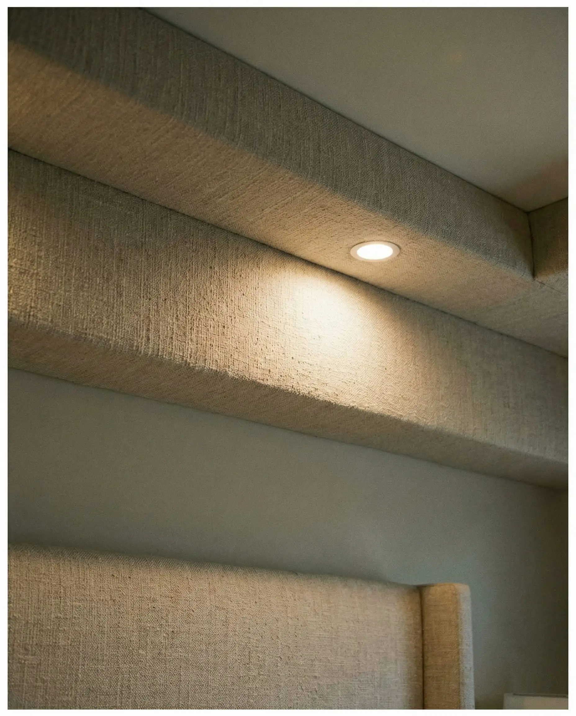 Détail d'un caisson de plafond de chambre recouvert de tissu de lin couleur avoine pour l'insonorisation.