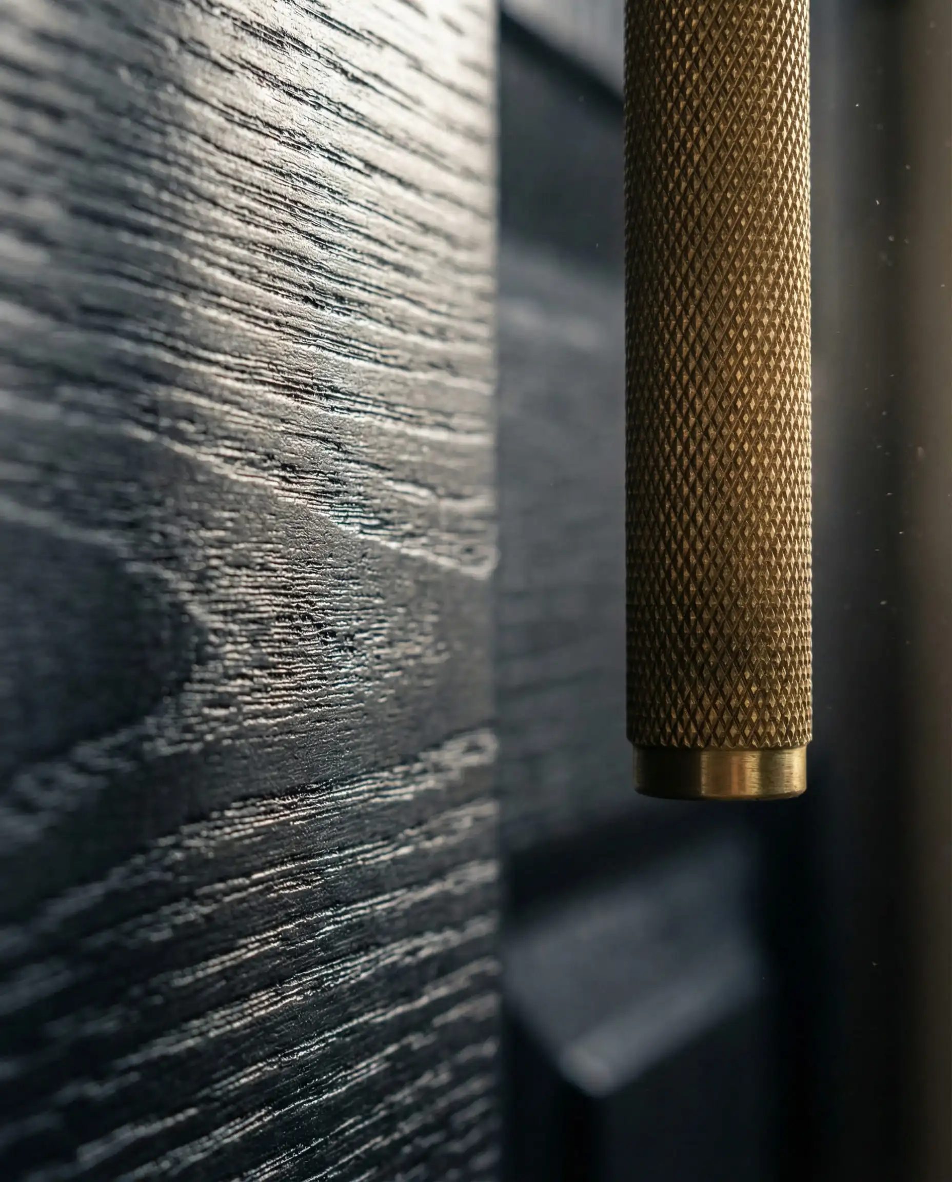 Gros plan macro de la texture d'une teinture en bois noir sur une porte d'entrée munie d'une poignée en laiton moleté.