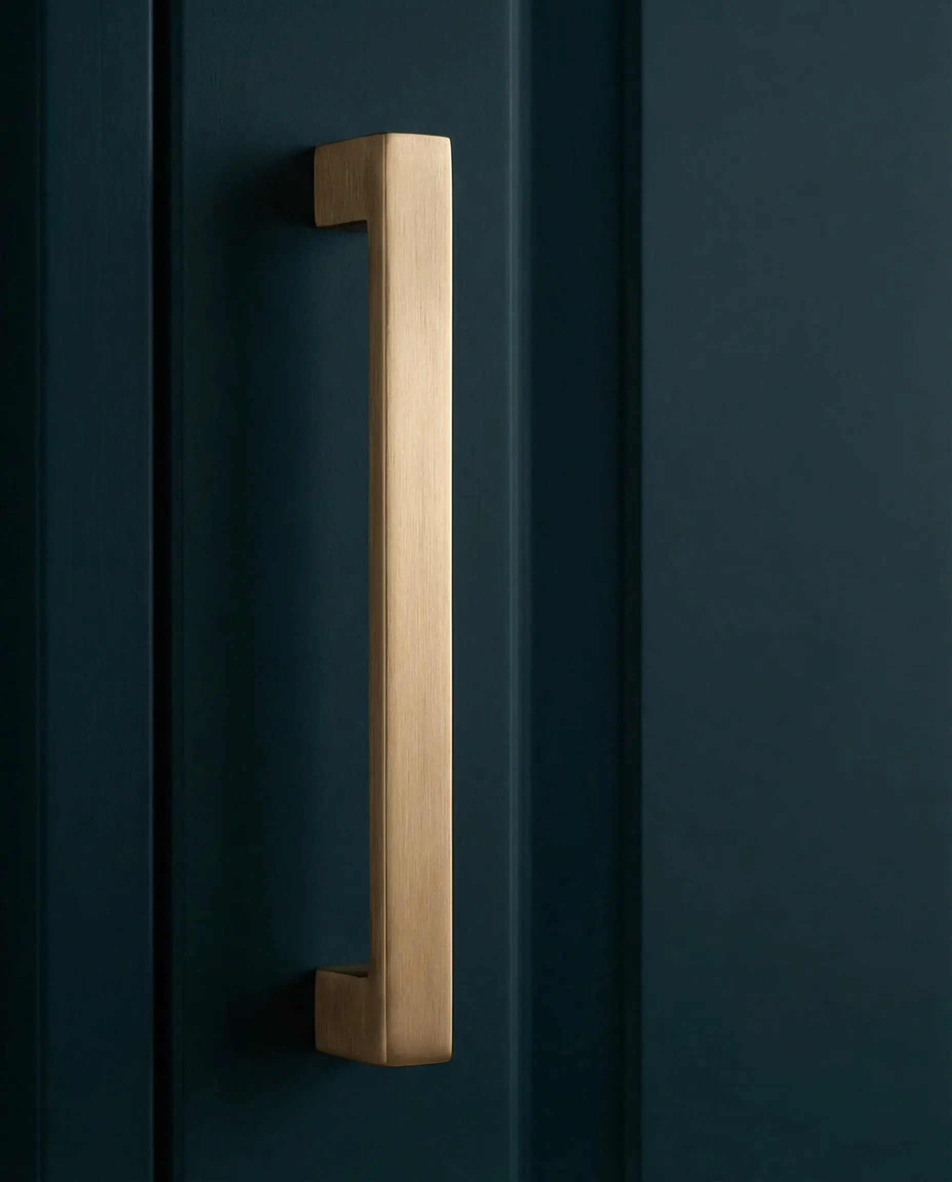 Poignée de porte rectangulaire en bronze brossé, montée sur une porte d'entrée bleu sarcelle foncé.
