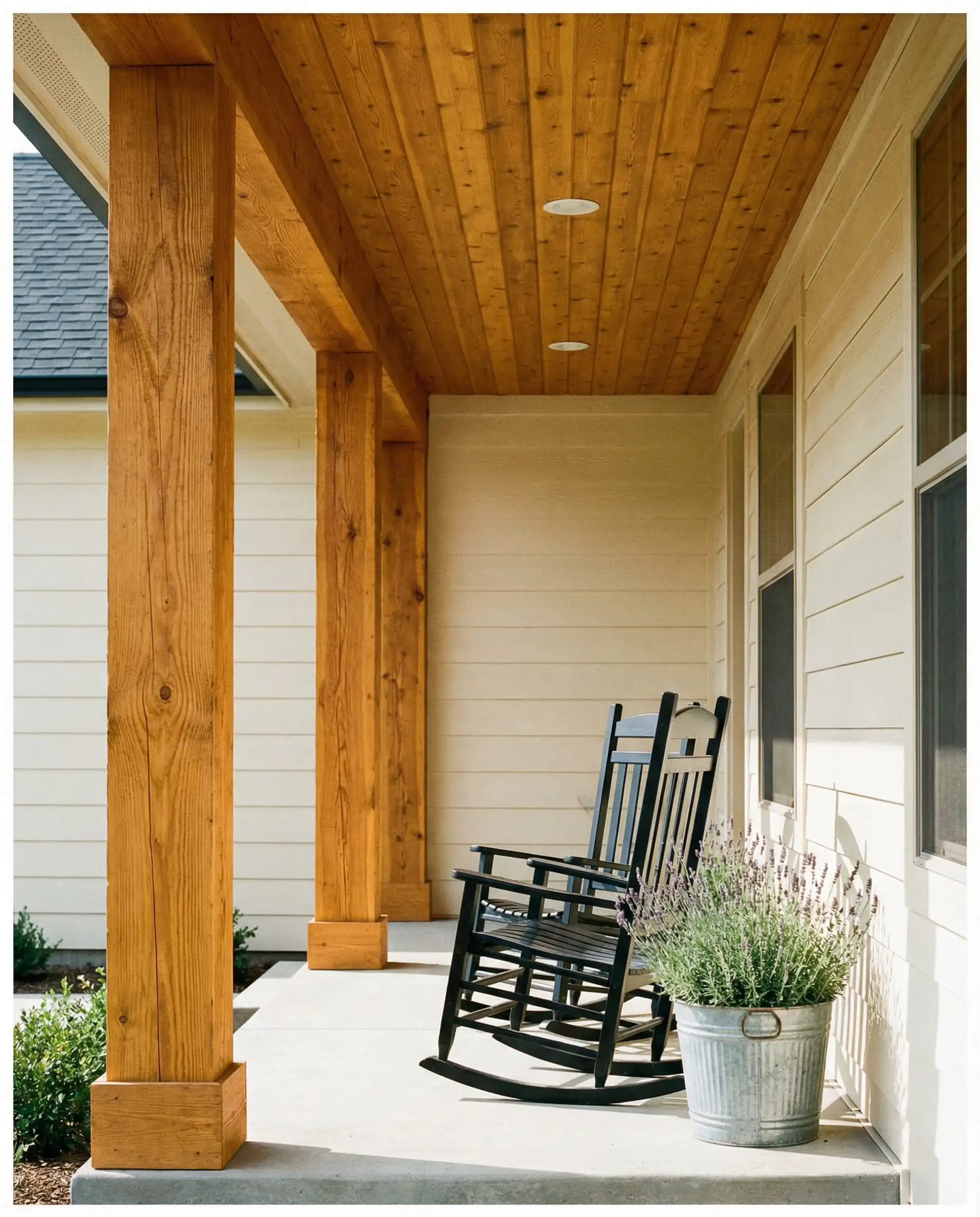 Close up of farmhouse front porch featuring raw stained cedar columns and rocking chair.