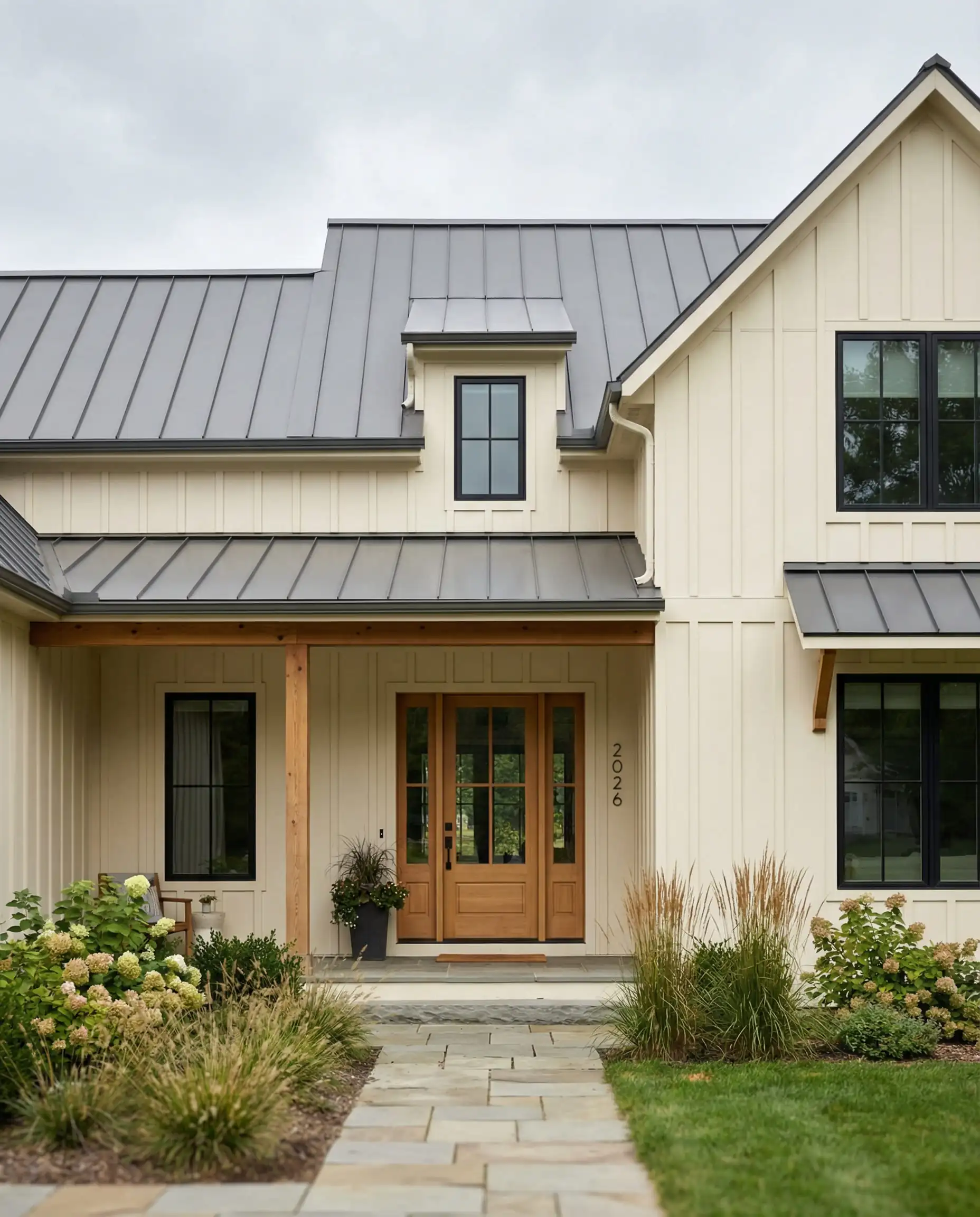 Modern farmhouse exterior with vertical siding painted in warm creamy white with metal roof.