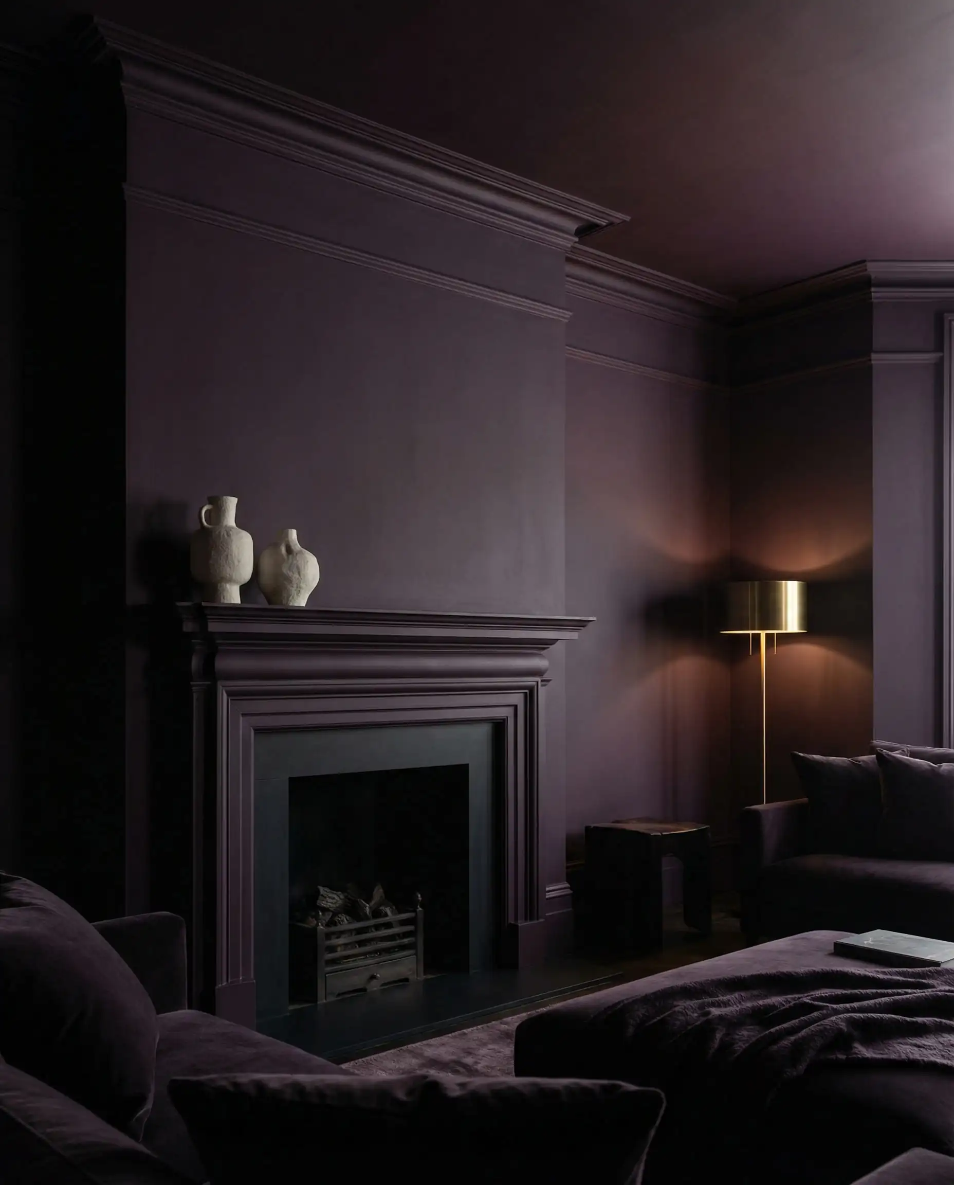 A living room fully 'Color Drenched' in a deep, matte 'Divine Damson' paint (blackened plum/purple). This living room features Matte Damson plum, dark wood, and white ceramic tones and a regal, introspective, dramatic cocooning atmosphere.