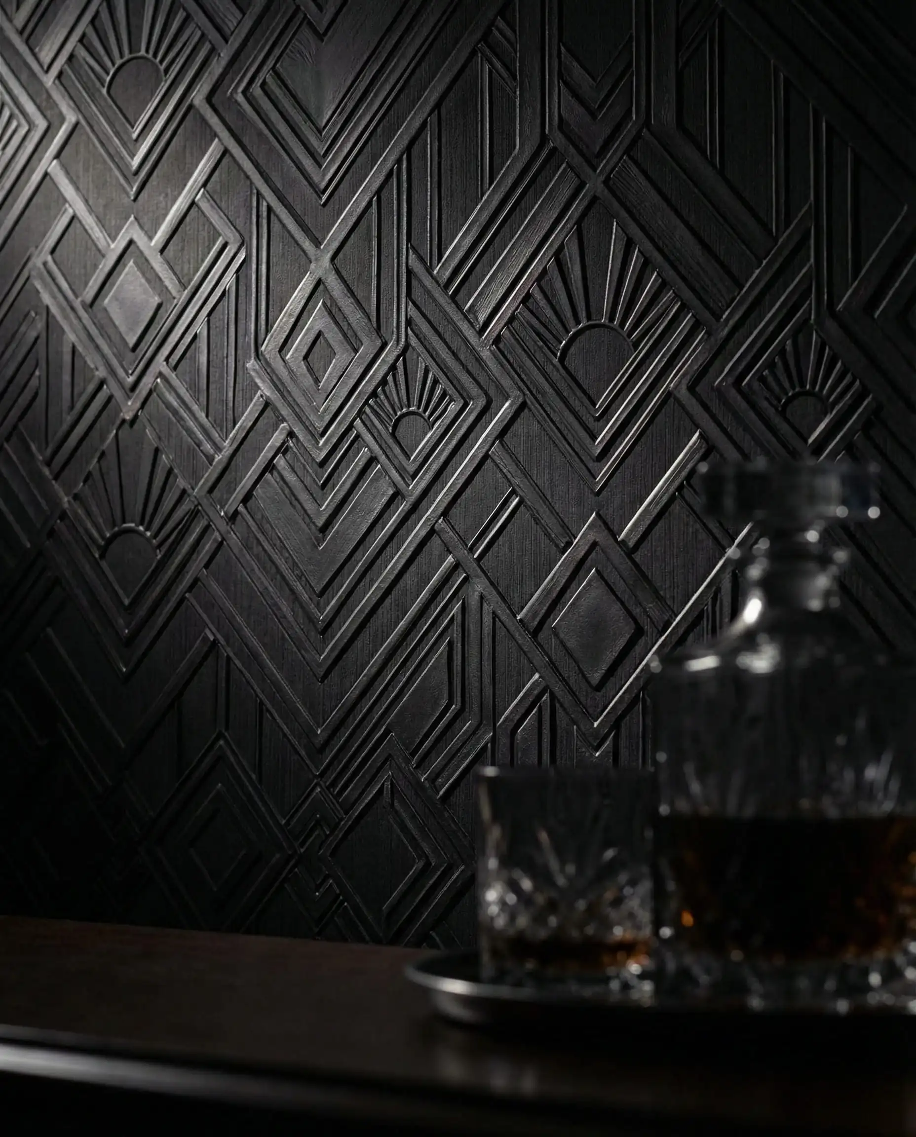 Dark charcoal vinyl wallpaper with a deep geometric embossed pattern creating high-contrast shadows.