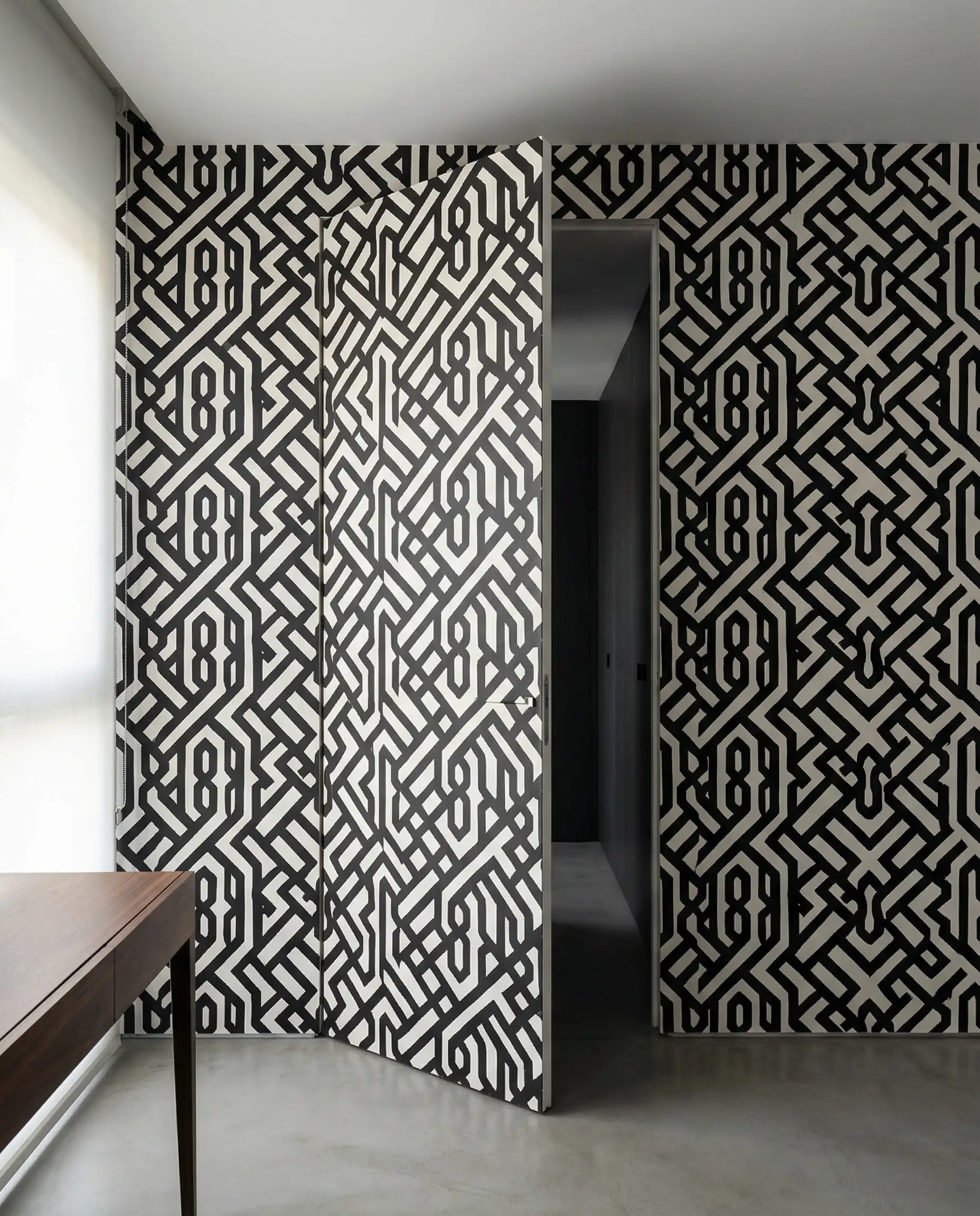 Mur moderne avec une porte cachée affleurante recouverte de papier peint géométrique.