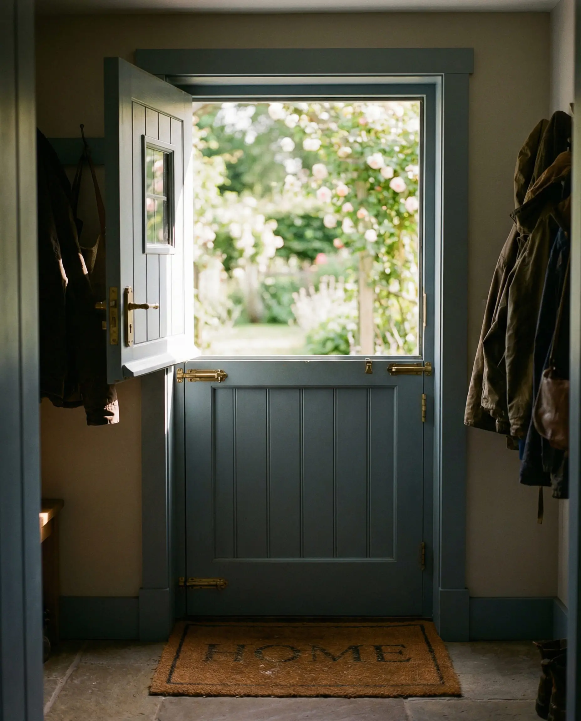 Blue-grey solid wood Dutch door with top half open to a garden view.