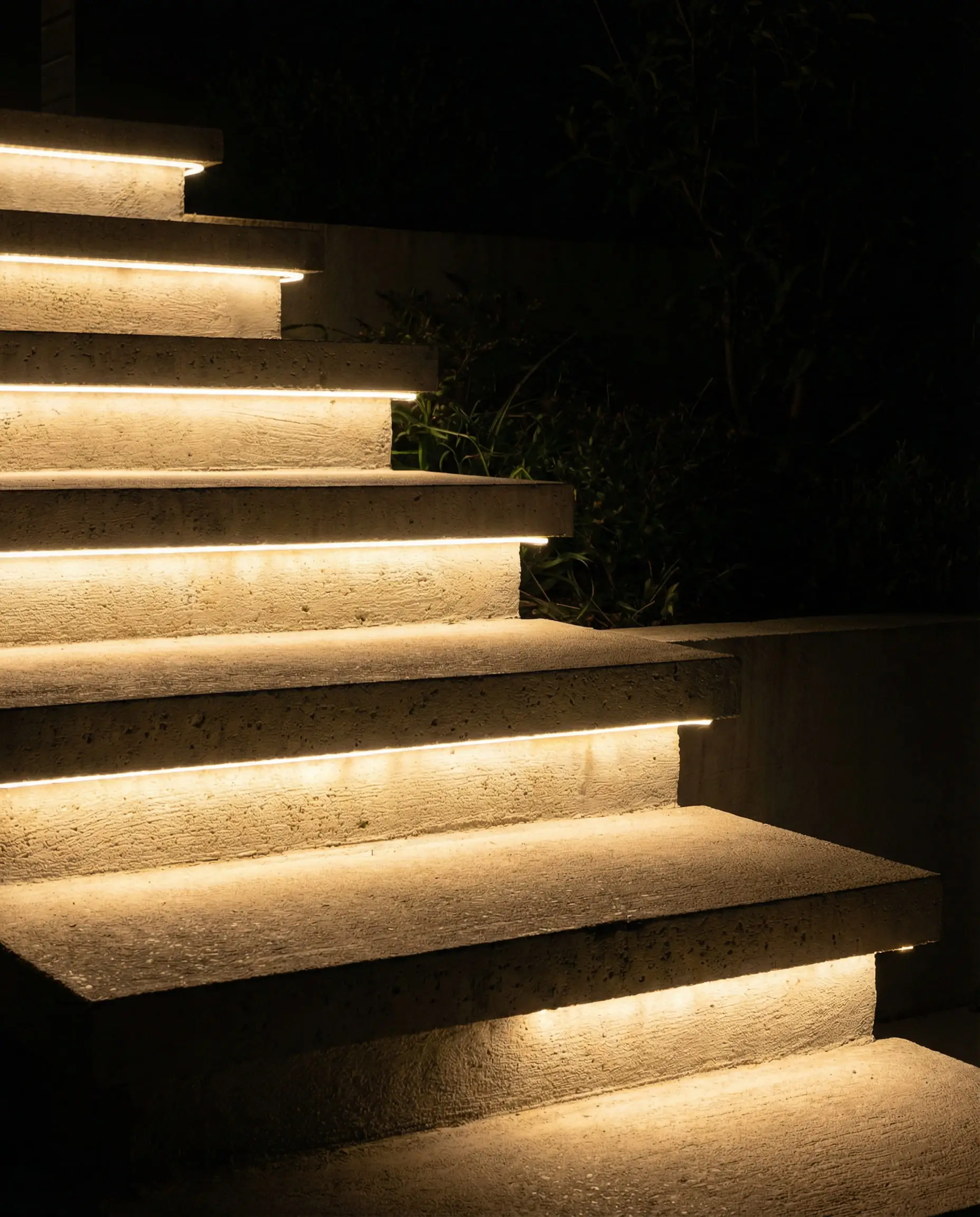 Floating concrete outdoor stairs illuminated by hidden LED strip lights underneath each step.