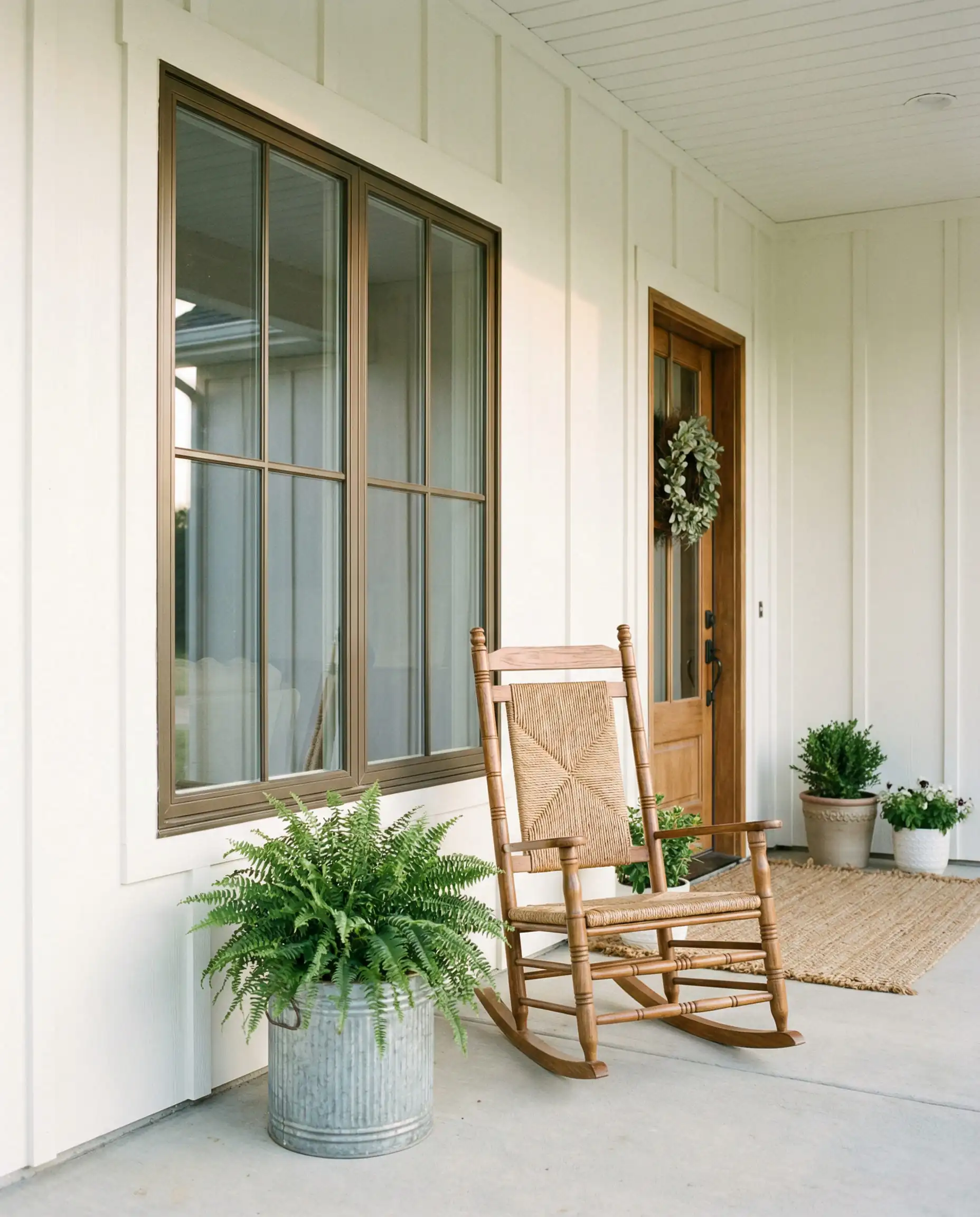 Modern farmhouse porch with creamy white siding and soft bronze window frames.