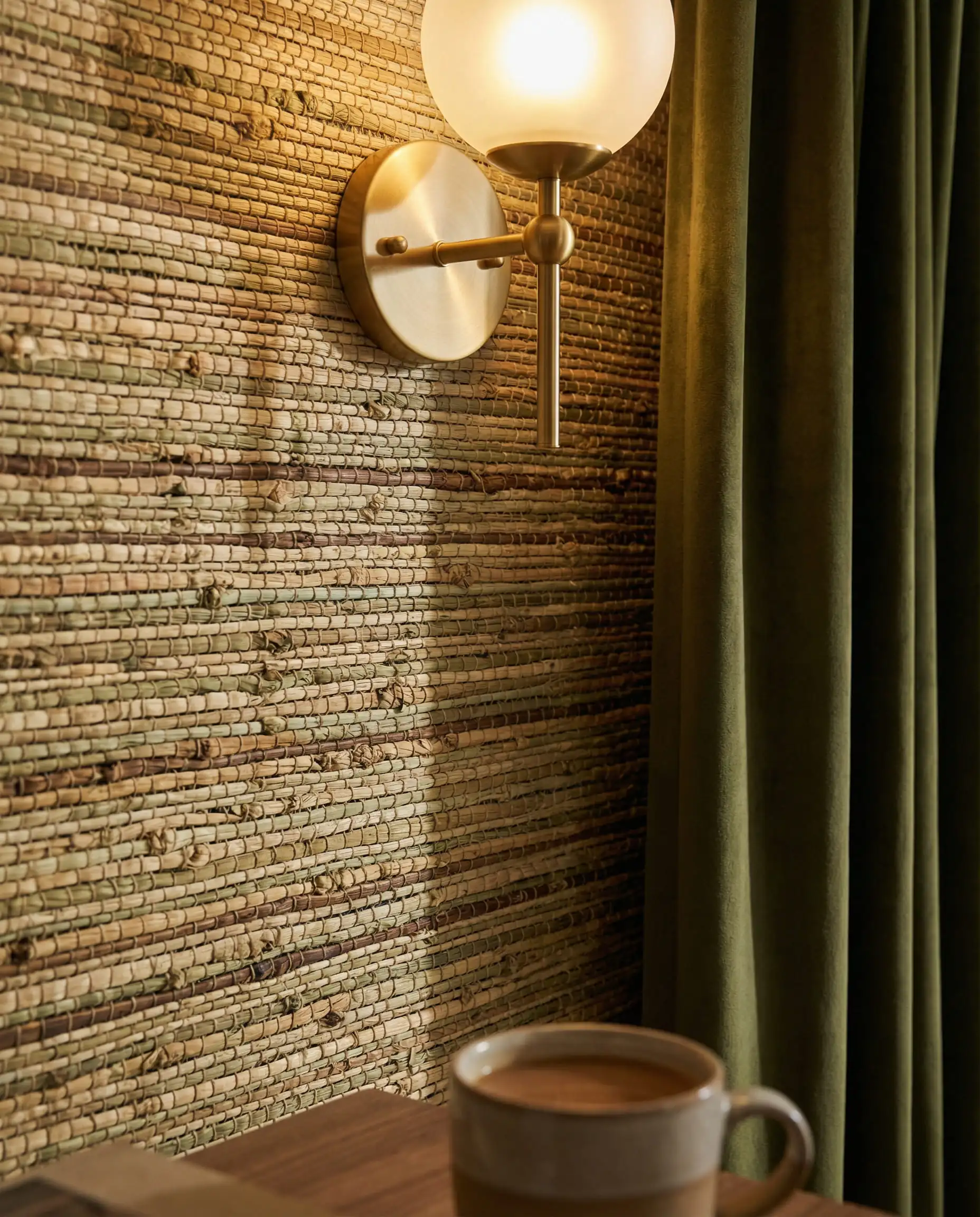 Close-up of natural sage green grasscloth wallpaper showing organic knots and horizontal weave texture.