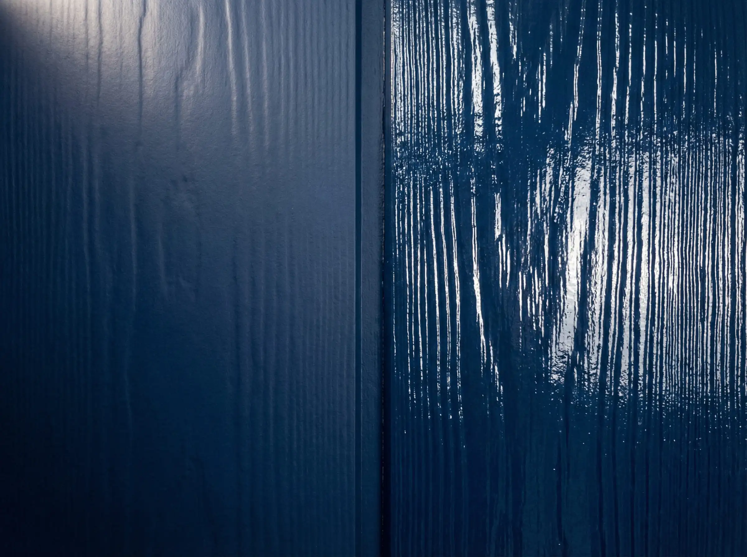 Split screen comparison of navy blue exterior paint showing the difference between a flat matte finish and a high gloss finish on wood siding.