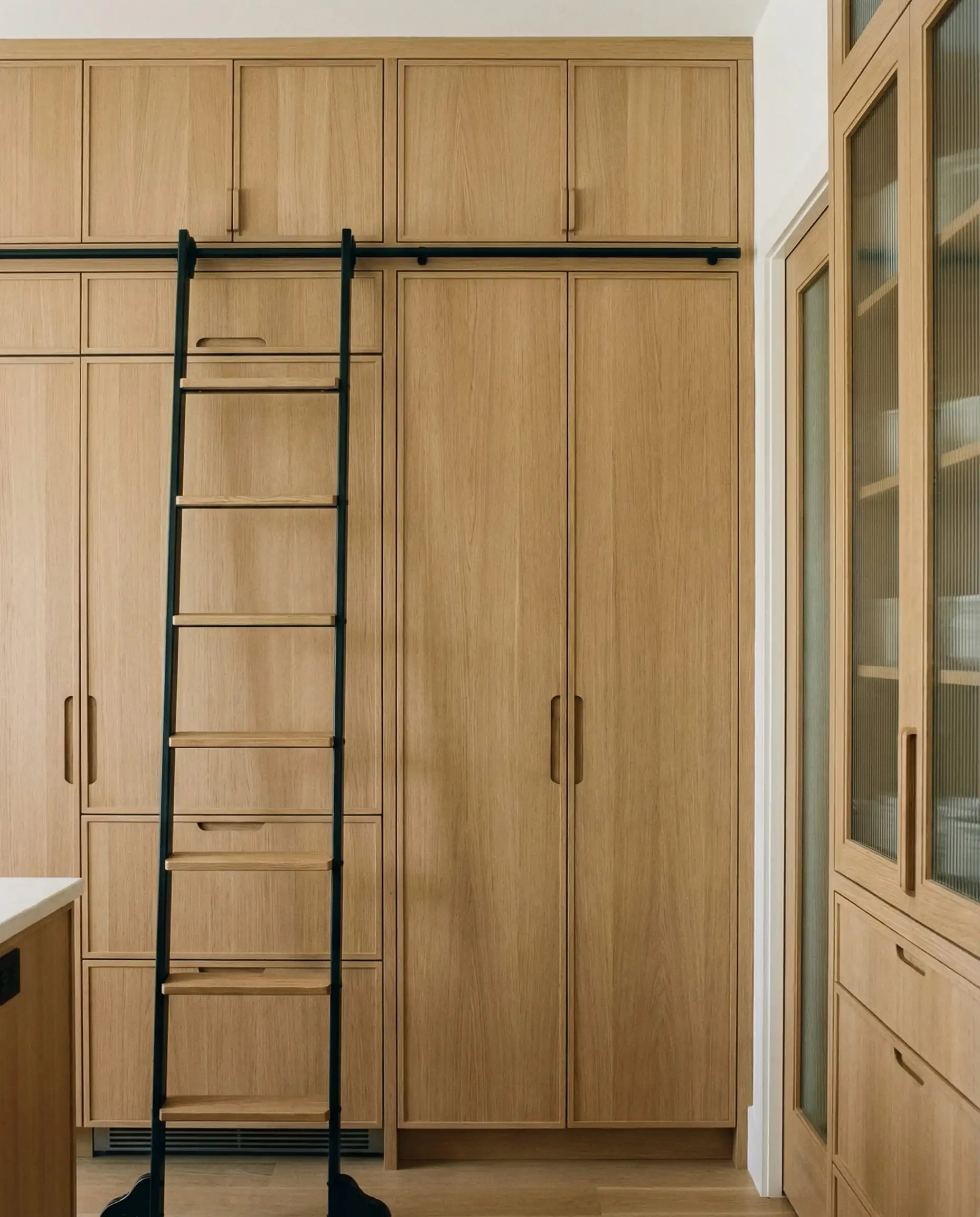 Wall of white oak kitchen cabinetry with fully integrated panel-ready refrigerator and dishwasher.