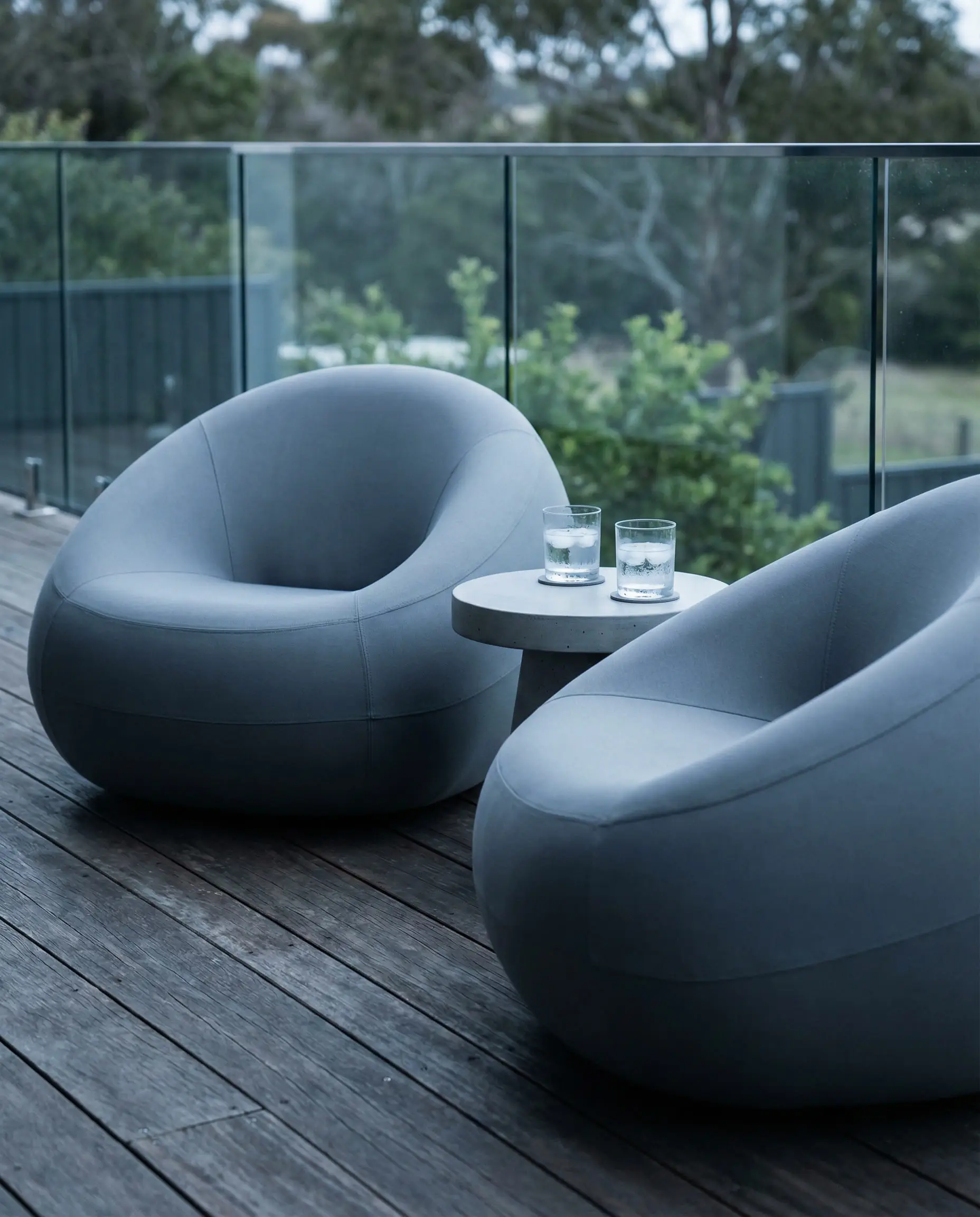 Two low-profile, organic pebble-shaped outdoor armchairs on a wooden deck.