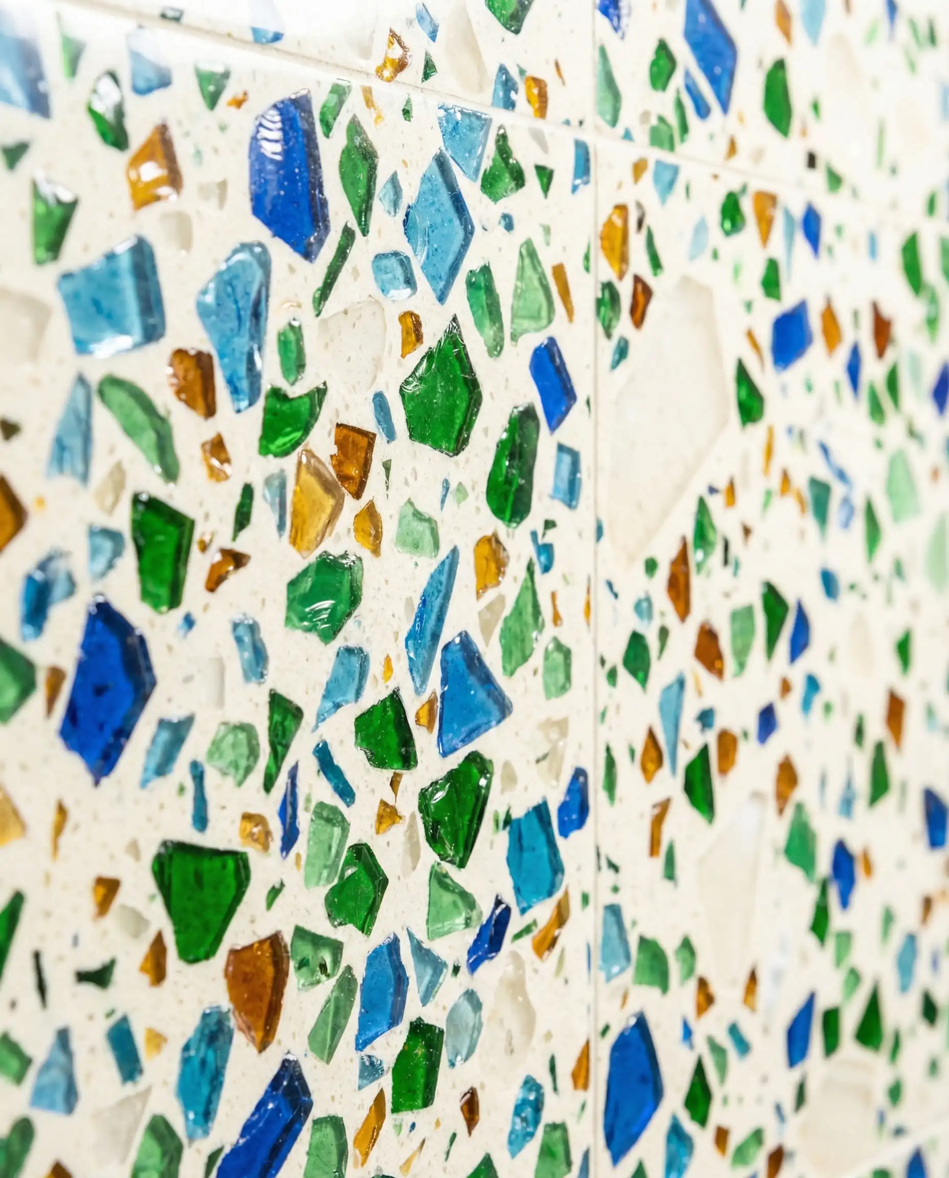 Une surface murale vibrante et durable revêtue de gros carreaux de terrazzo épais fabriqués à partir de morceaux de verre recyclé.