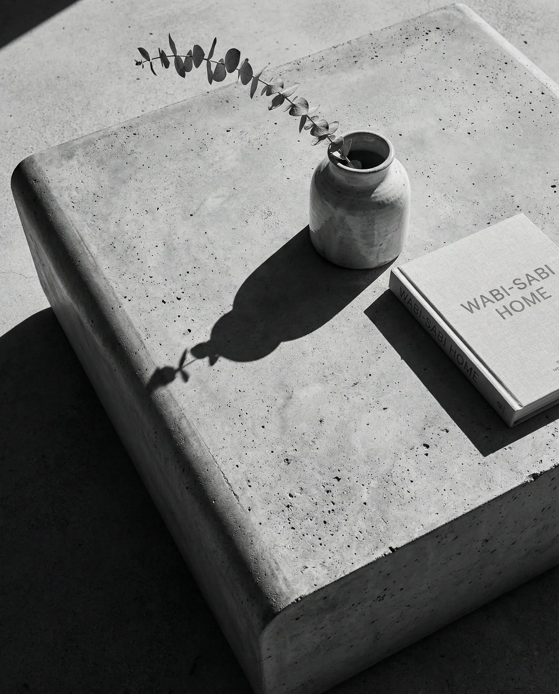 Top-down view of a round, raw concrete coffee table with soft edges styled with a vase.