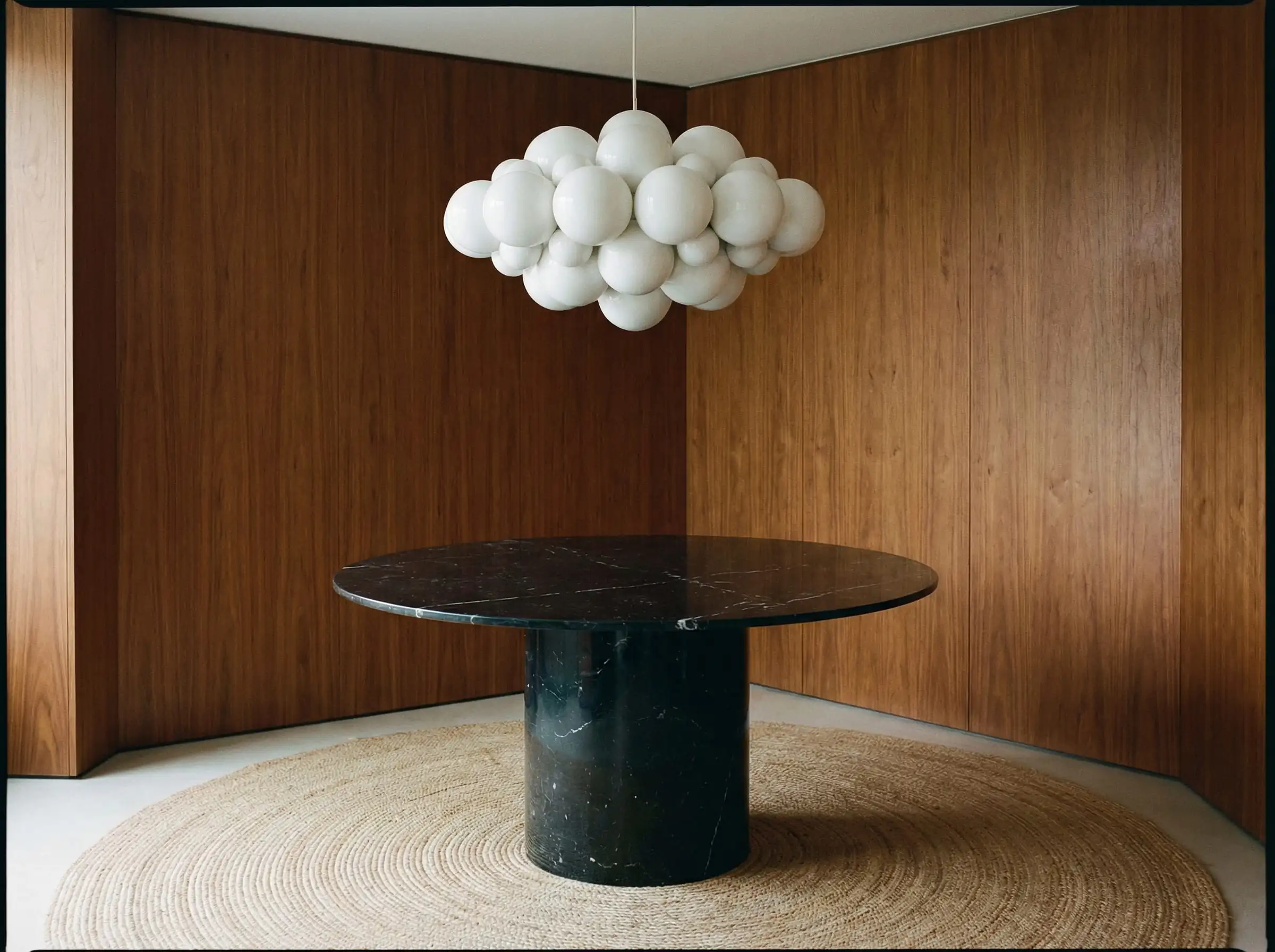 Luminaire rond en forme de nuage de bulles suspendu au centre d'une table à manger ronde en marbre noir.