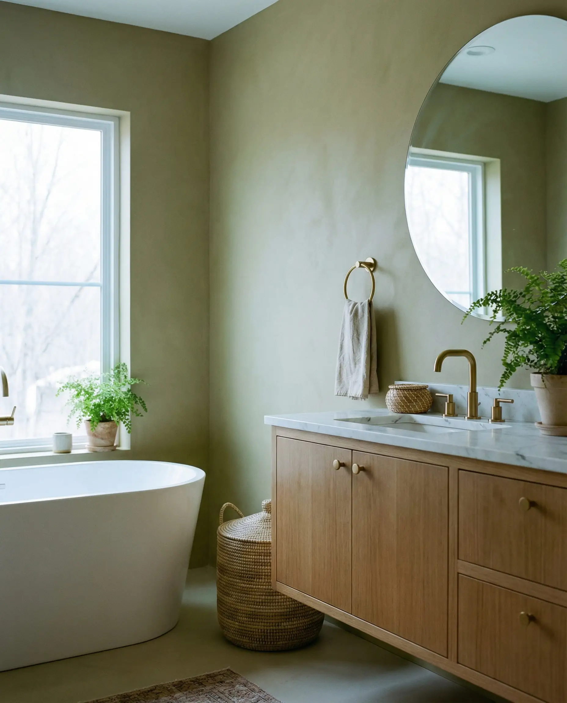 Une salle de bain lumineuse et aérée avec des murs peints dans un vert olive doux et sourd, fonctionnant comme un neutre.