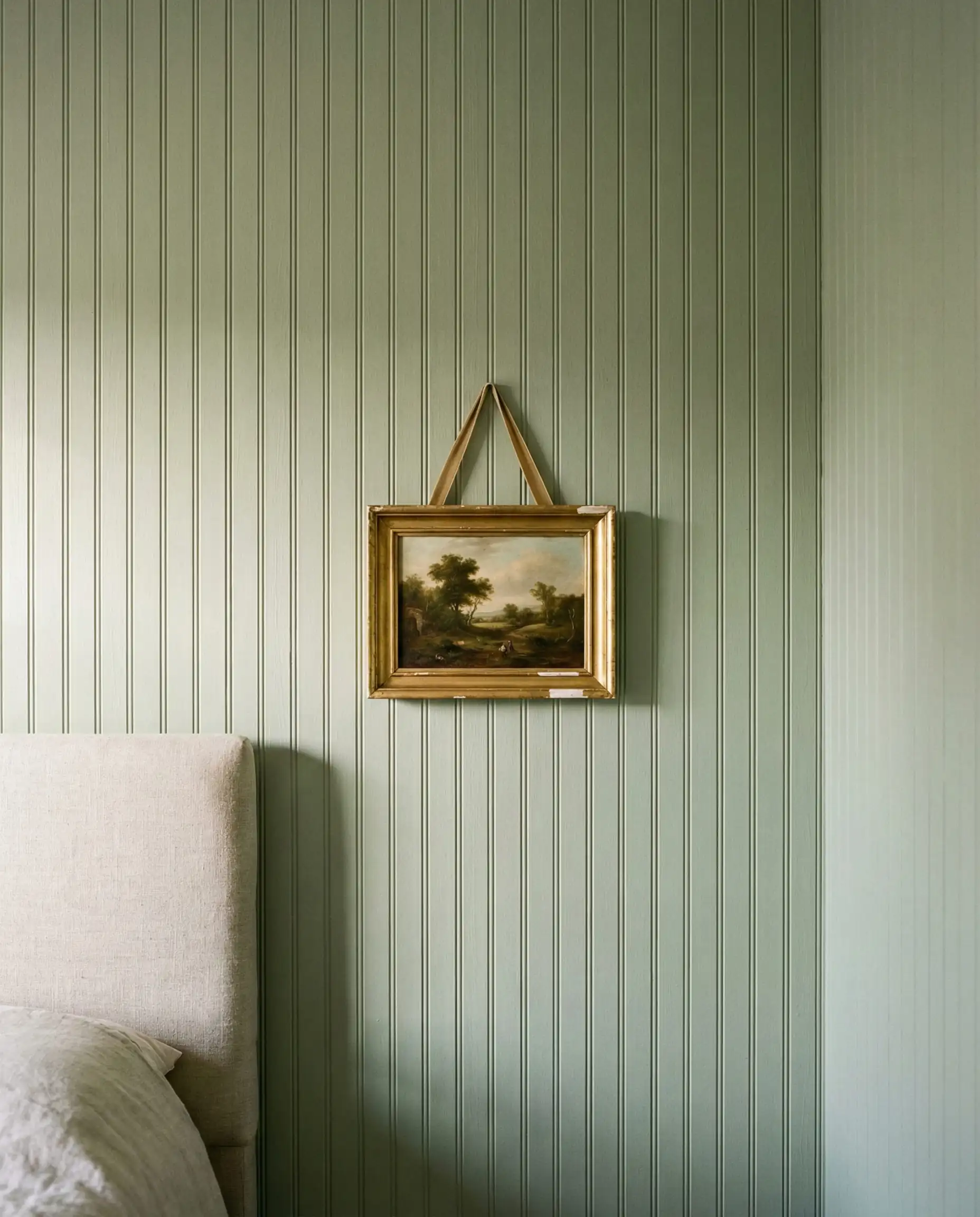 Bedroom wall featuring floor-to-ceiling vertical tongue and groove paneling painted in sage green.