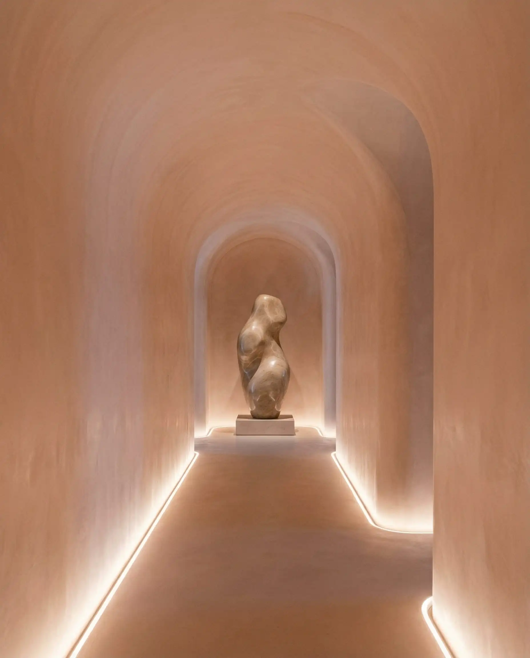 Couloir minimaliste avec une transition courbe harmonieuse du mur au plafond (alcôve) et un éclairage du sol au plafond.