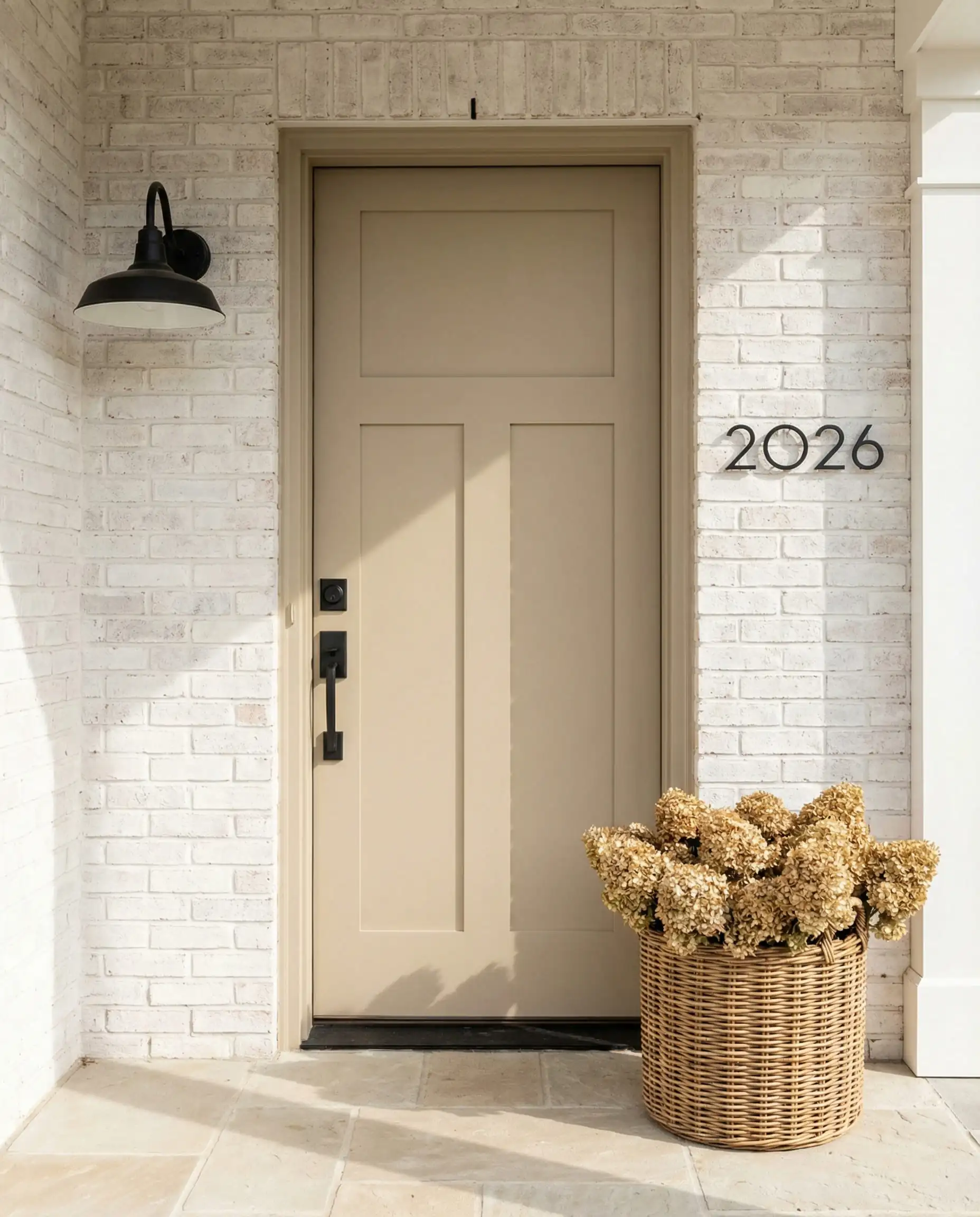 Porte d'entrée beige kaki universelle sur une maison en briques blanches avec éclairage mural moderne par appliques noires.