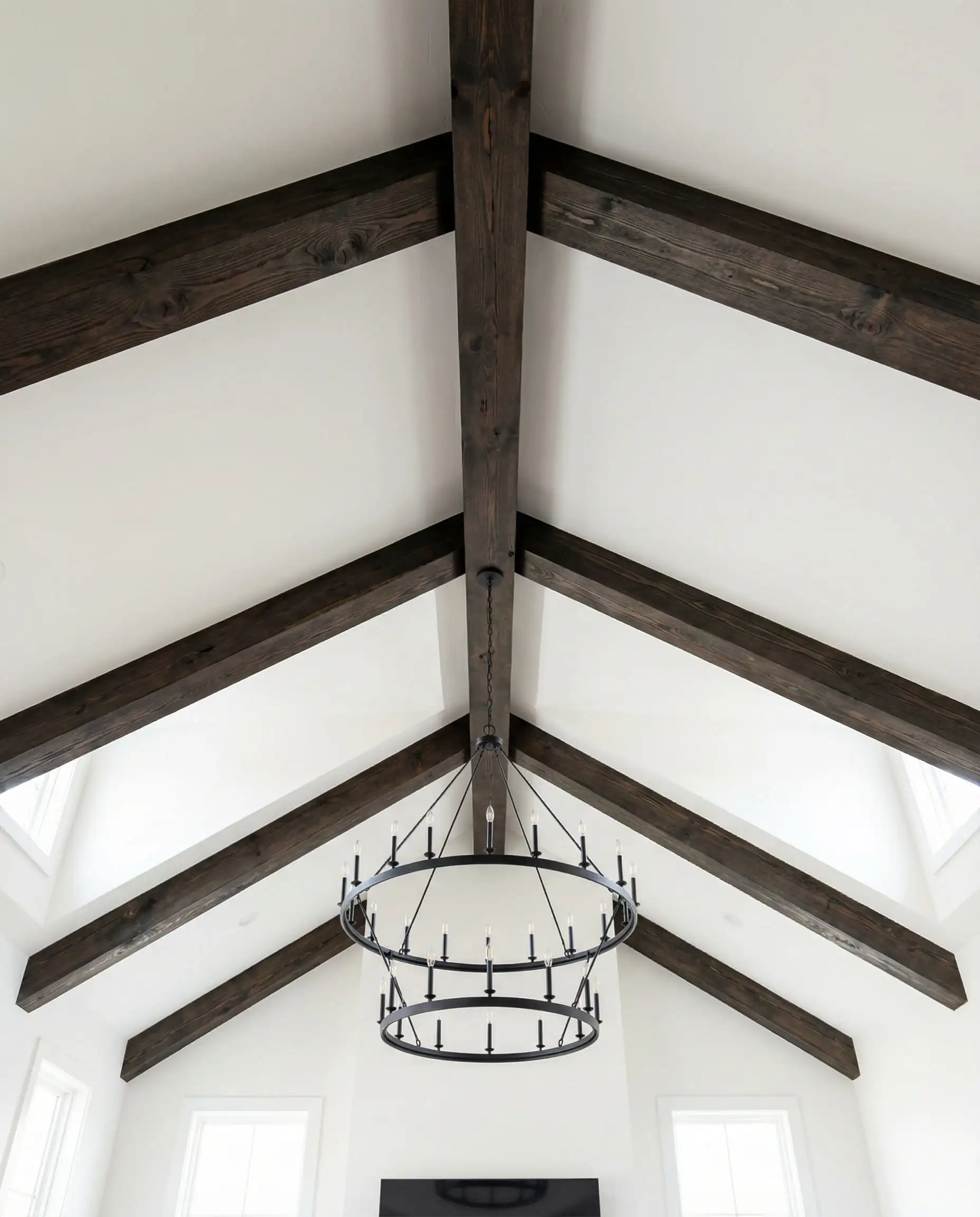 Living room looking up at white plaster vaulted ceiling with contrasting dark stained heritage oak beams.