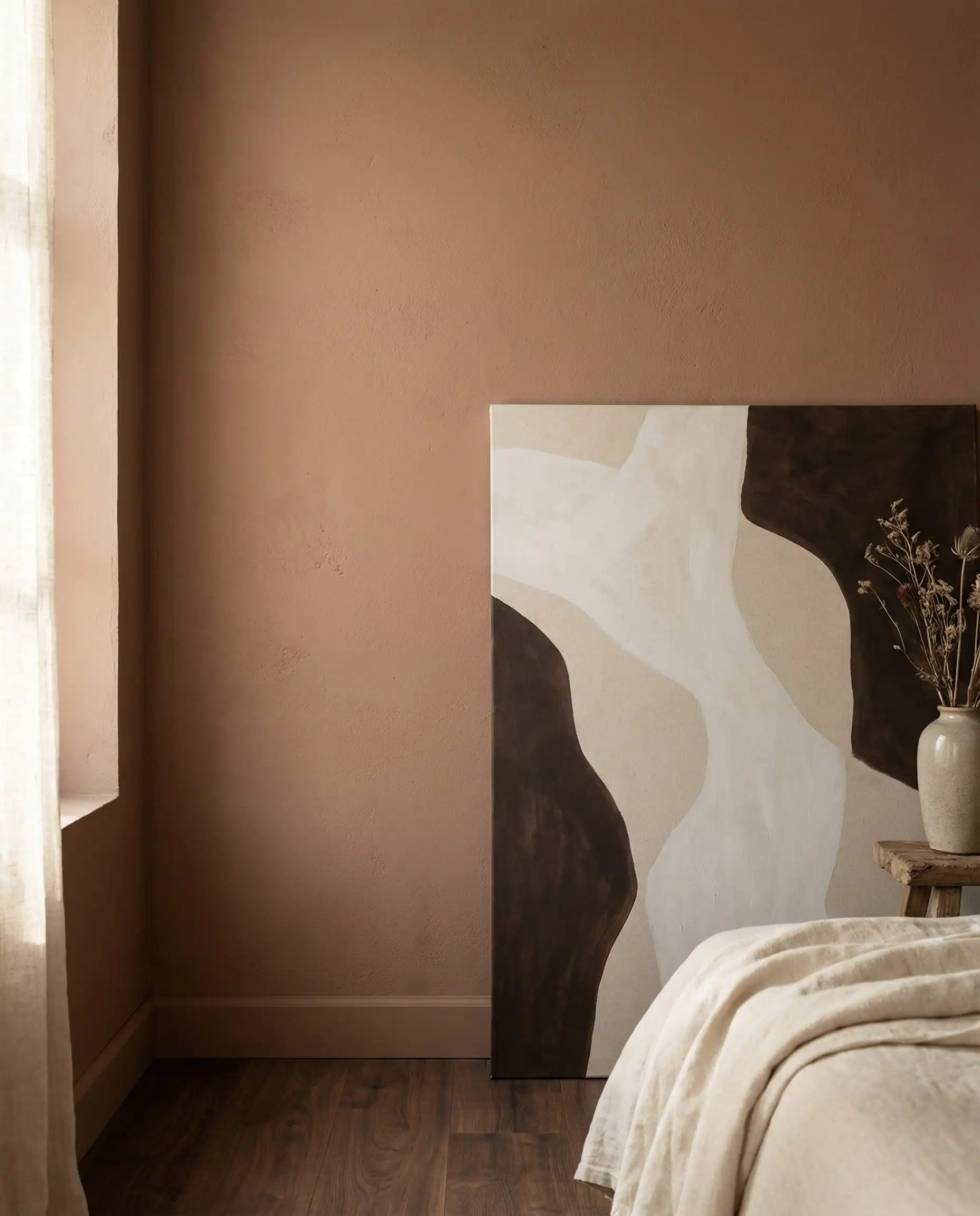 A detail shot of a bedroom wall painted in a soft, light cinnamon/nutmeg brown. This bedroom features Cinnamon brown, off-white, and dark wood floor tones and a tranquil, baking-spice neutrals, soft atmosphere.