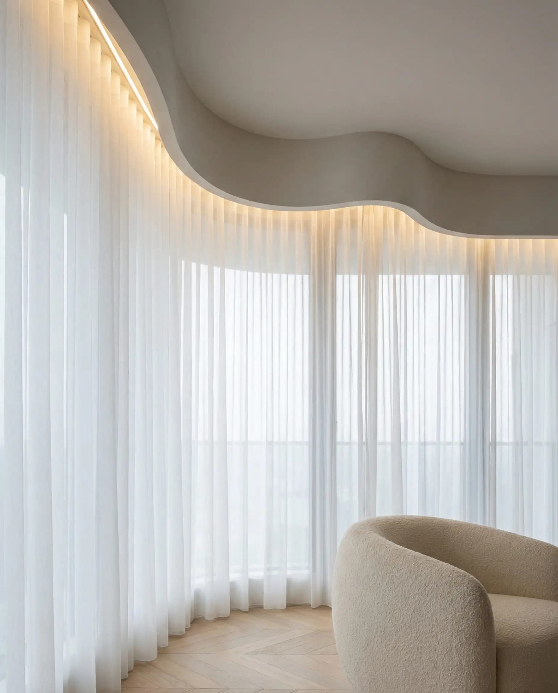 Mur vitré d'un appartement de luxe doté d'un faux plafond ondulé dissimulant des tringles à rideaux avec des accents LED.