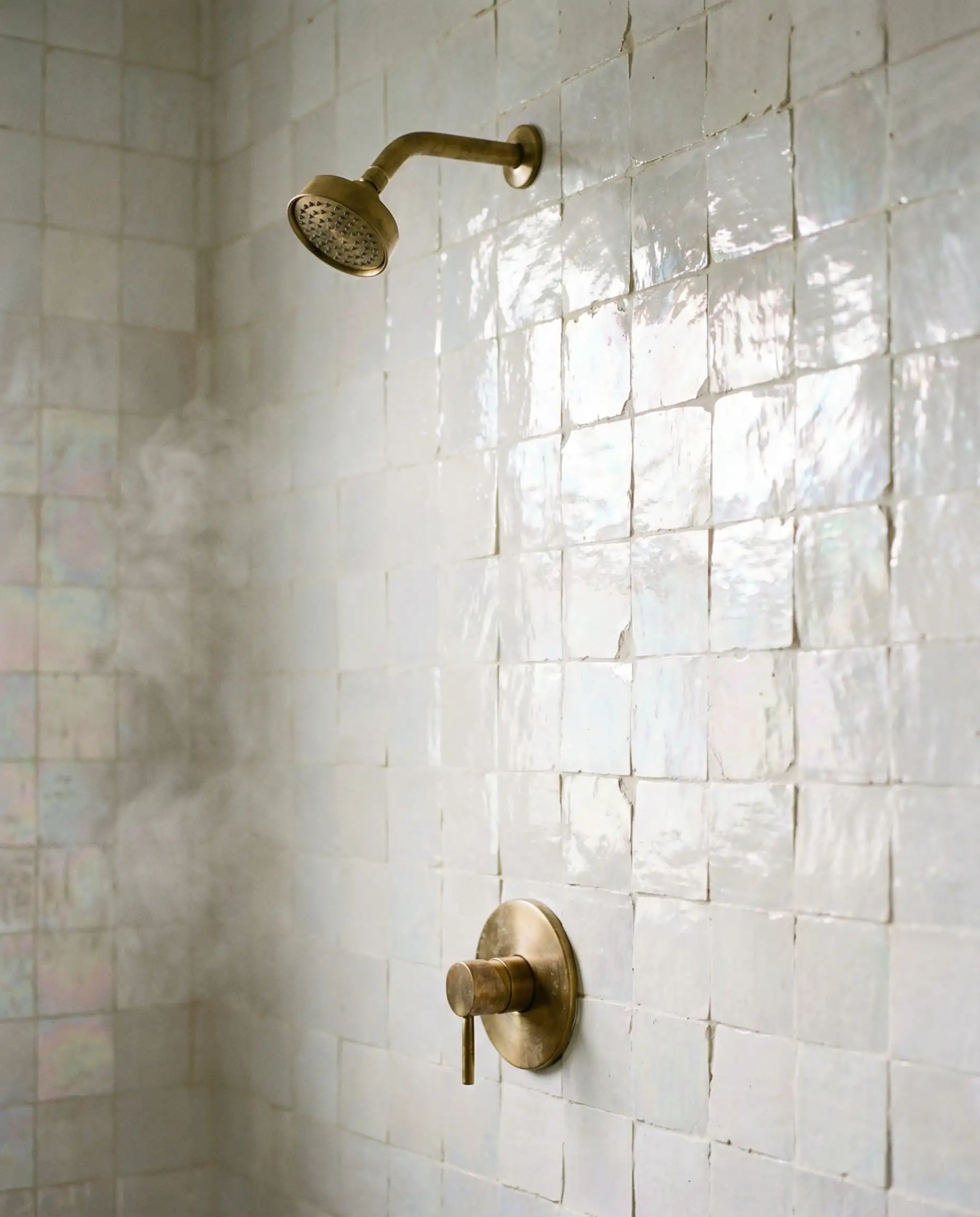 Walk-in shower featuring handmade pearlescent white Zellige tiles with uneven texture.