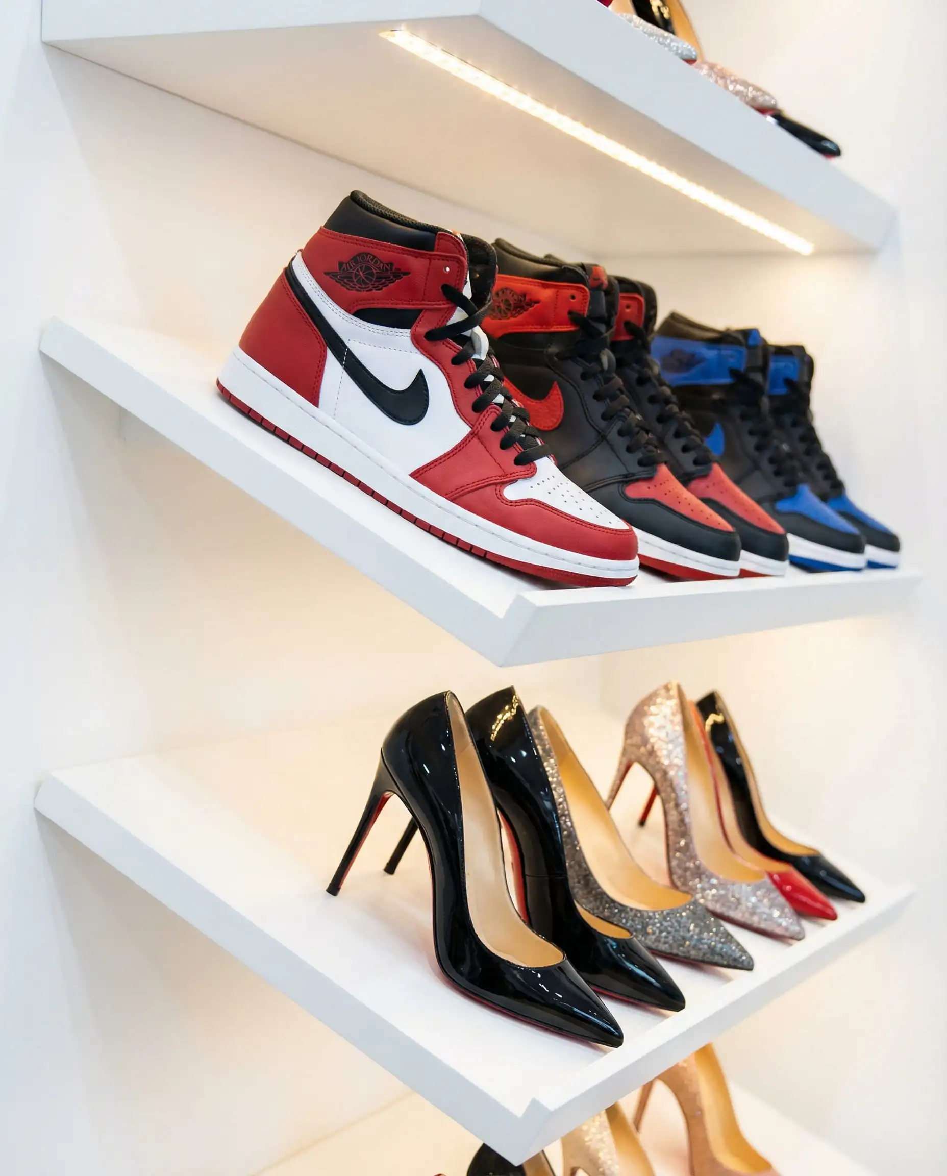 White angled shoe shelves with heel catches and LED lights displaying designer sneakers.