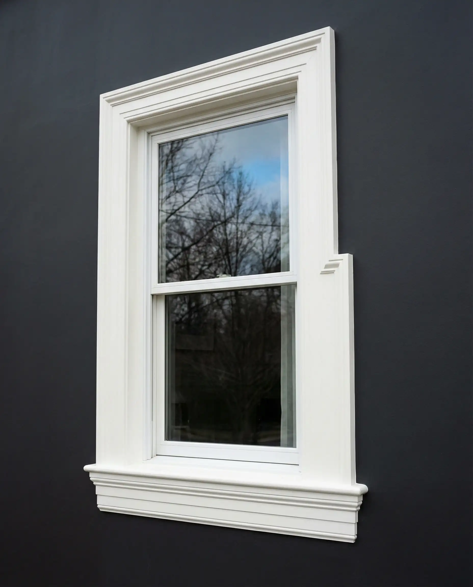 High contrast architectural detail of a window with bright white trim (Behr Polar Bear) set against a dark charcoal gray wall.