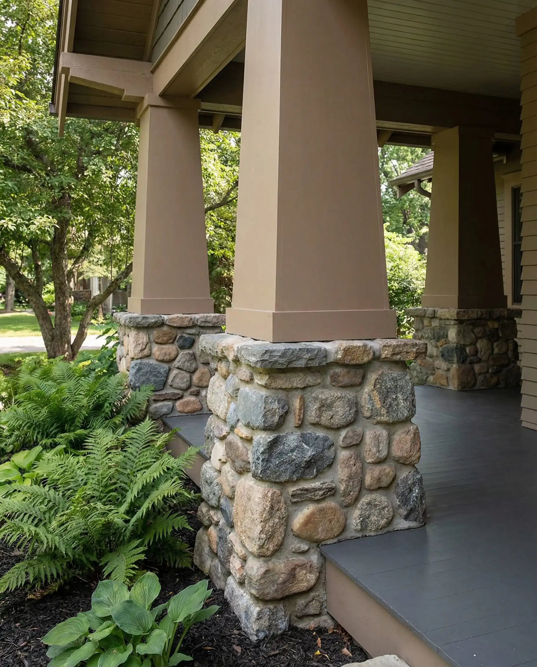 Low angle shot of Craftsman tapered porch columns with stone bases and upper wood painted in Behr Stone Brown to match the mortar.