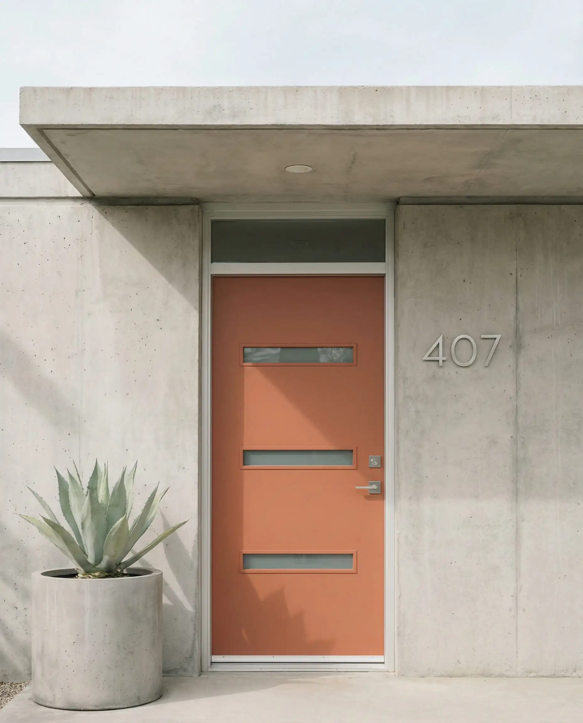 Minimalist modern entrance with gray concrete walls and a geometric front door painted in Behr Terra Cotta Urn.