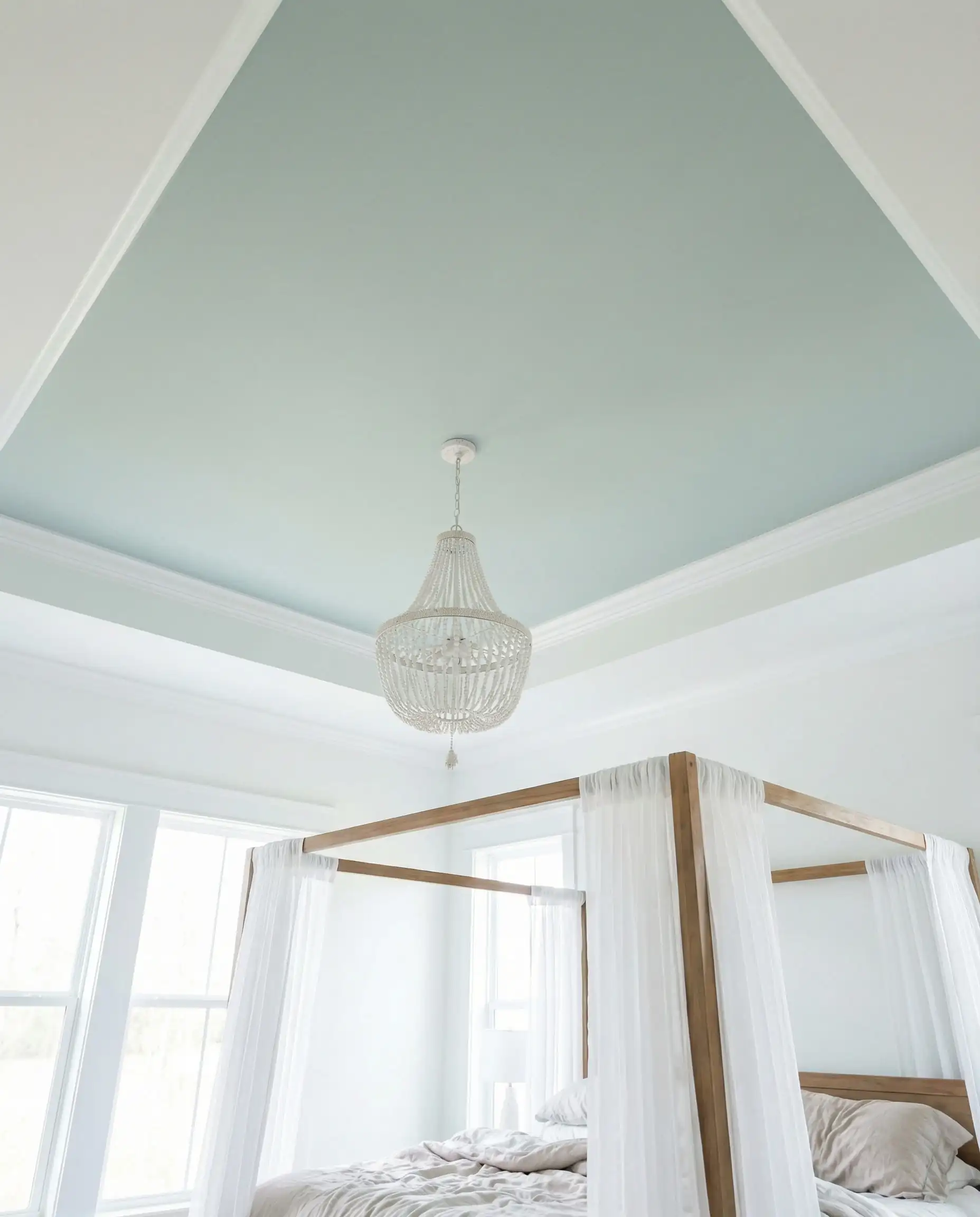 Bedroom ceiling painted in pale blue-green Behr Watery with a white chandelier.