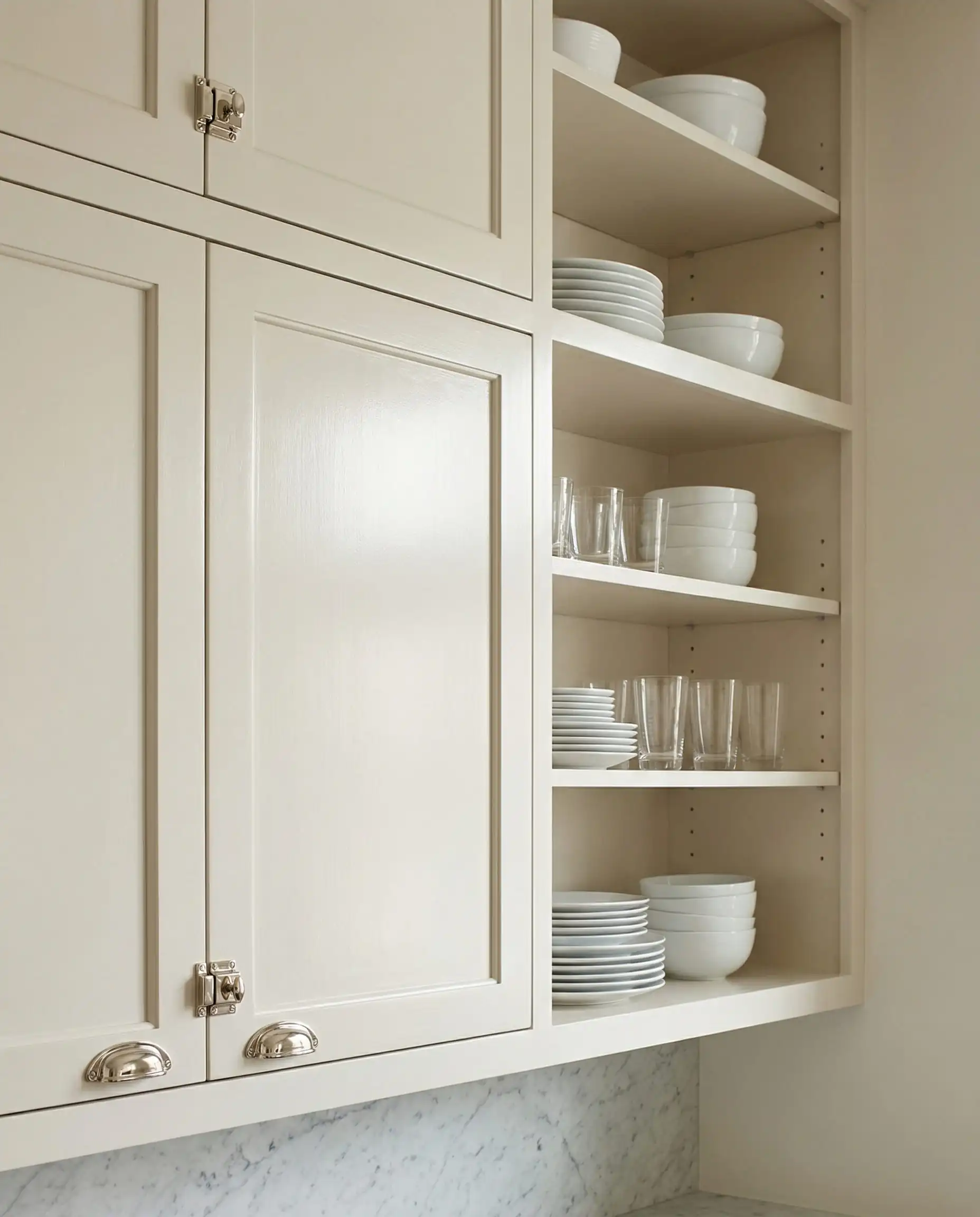 Editorial shot of upper kitchen cabinets painted in Benjamin Moore White Dove with polished nickel hardware.