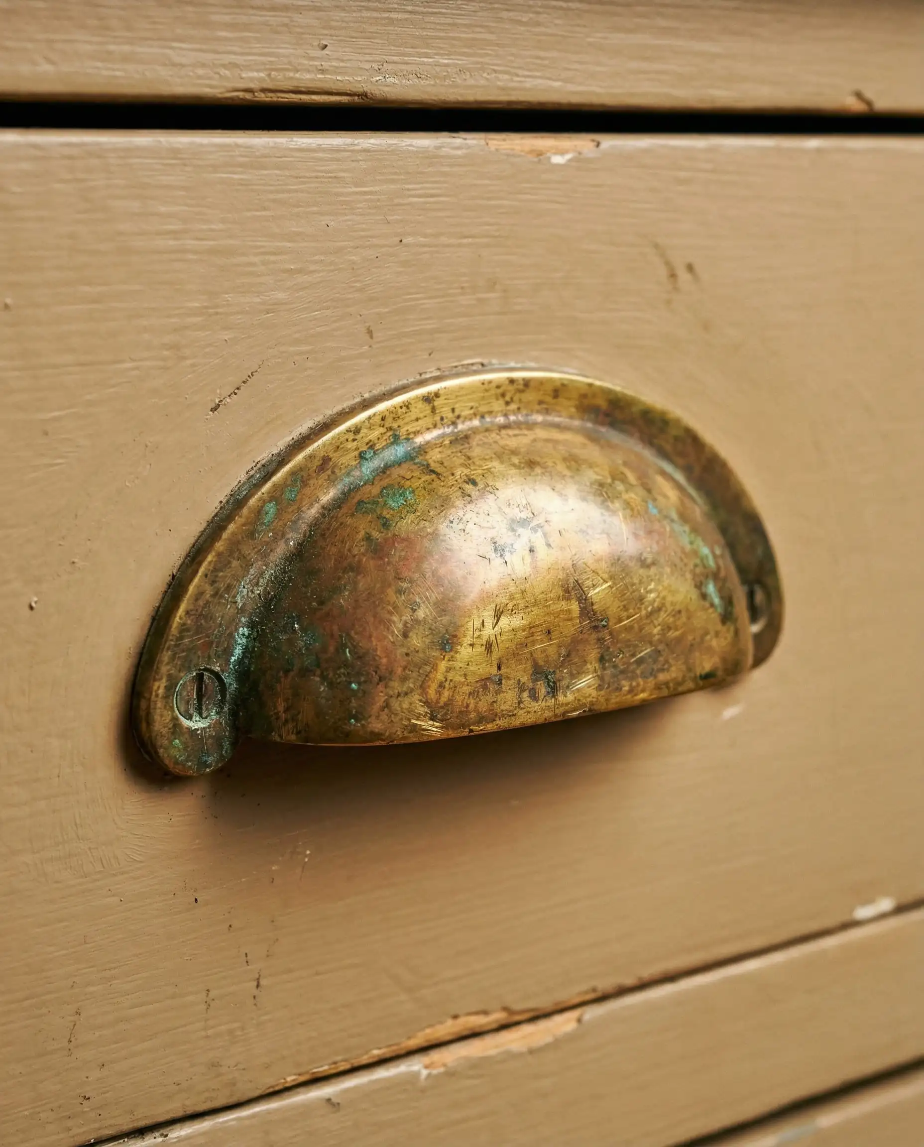 Macro of unlacquered brass hardware on Sherwin-Williams Universal Khaki cabinet.