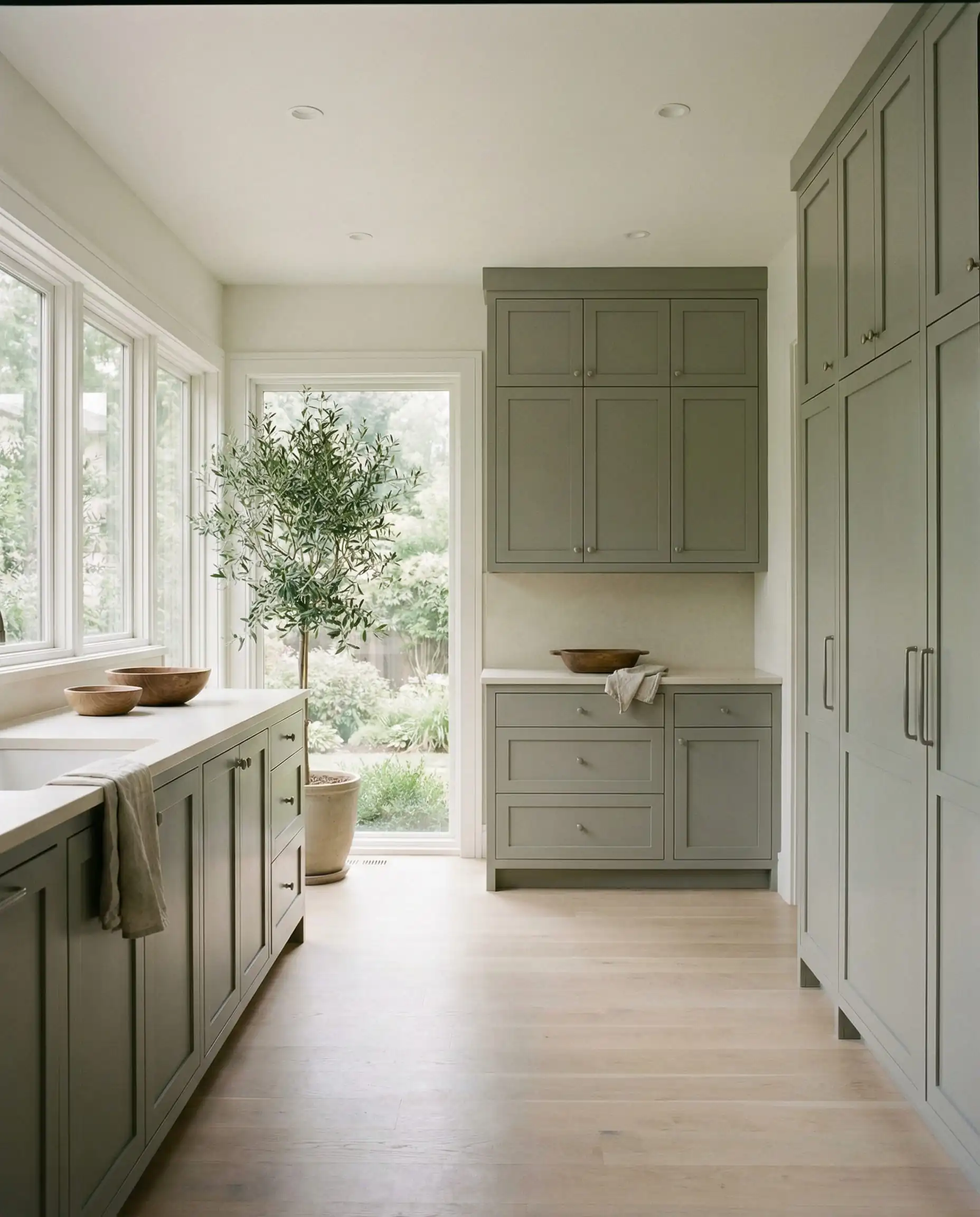 Full kitchen with uppers and lowers painted in Sherwin-Williams Evergreen Fog SW 9130 creating a spa-like feel.