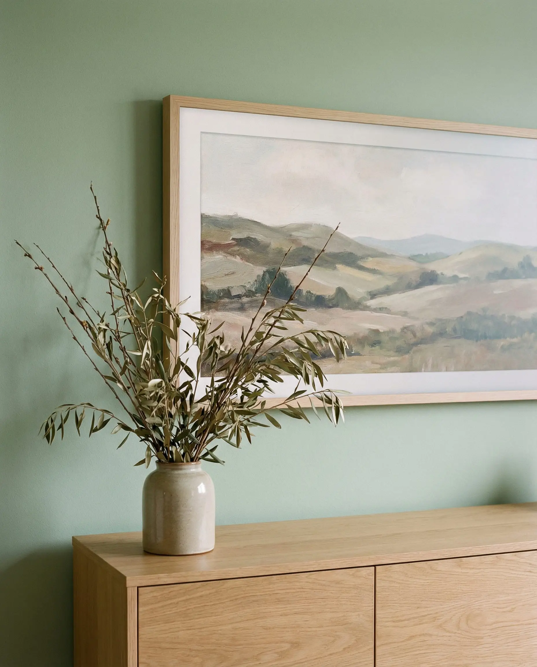 Samsung Frame TV displaying landscape art above a wooden console.