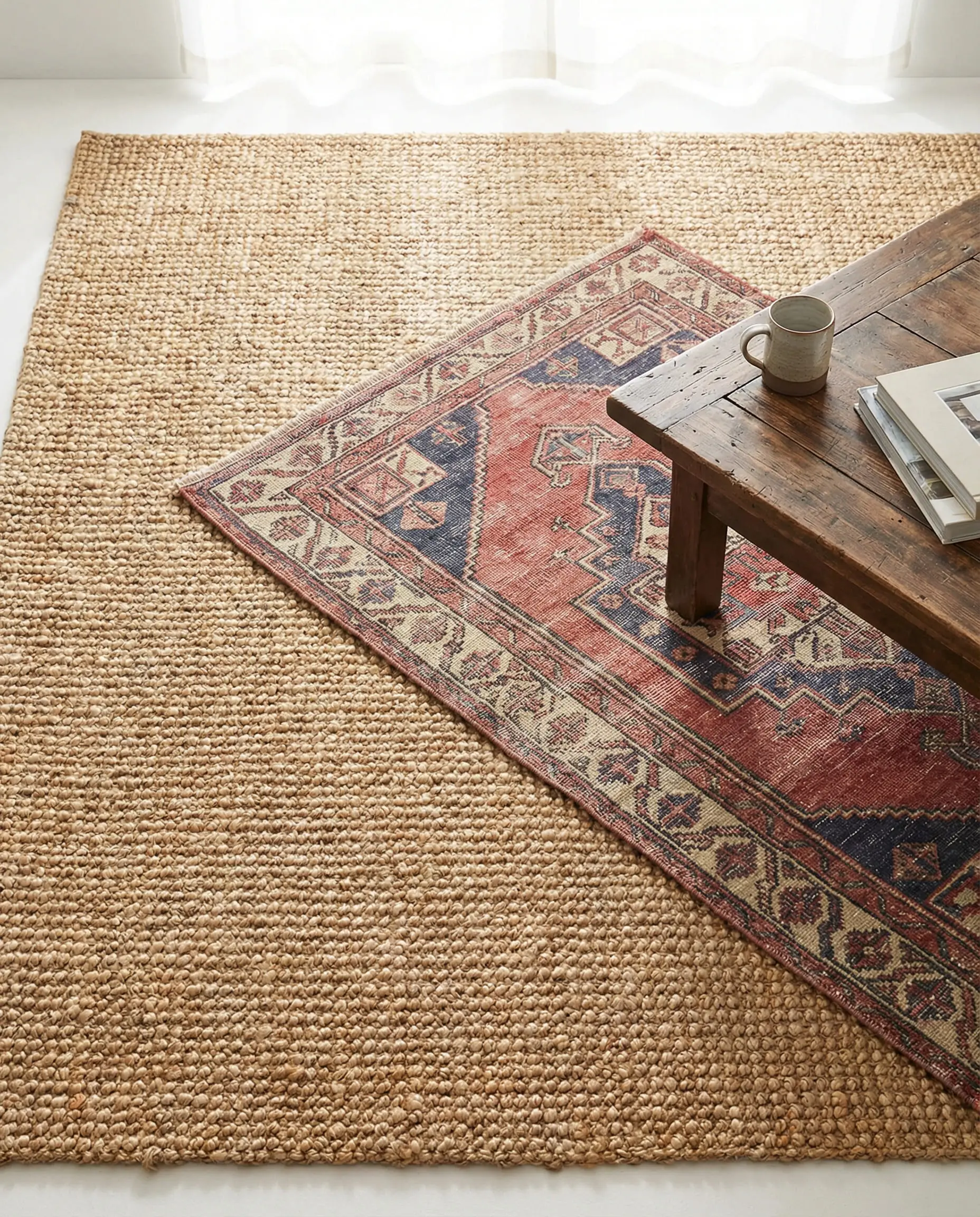Vintage Turkish rug layered diagonally over a large jute area rug.