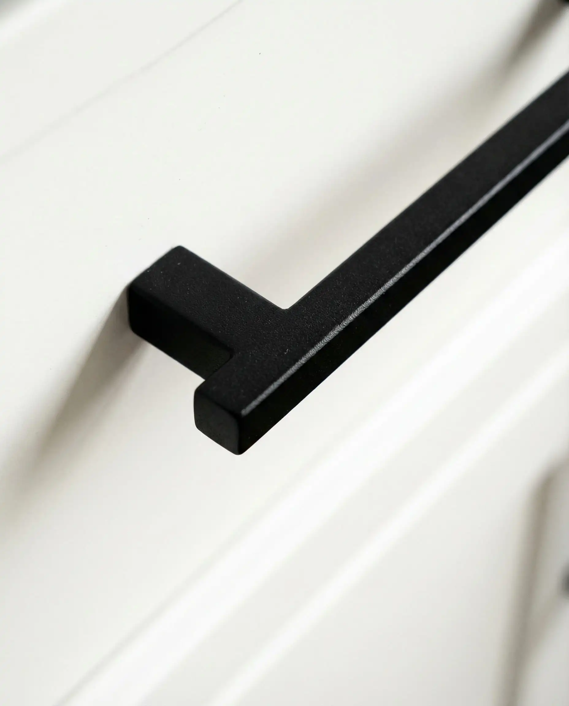 Macro of matte black hardware on Sherwin-Williams Pure White cabinet.