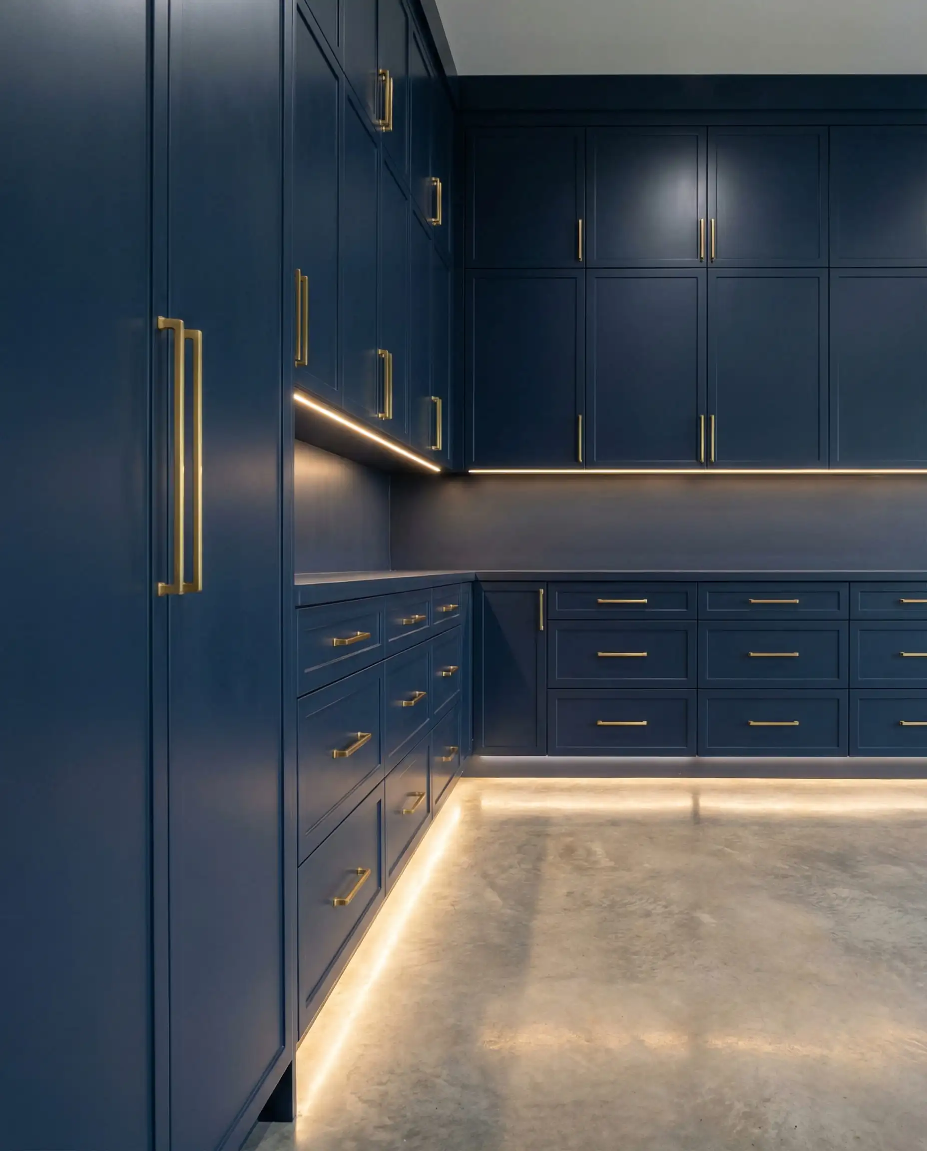 Custom garage cabinetry painted navy blue to match the navy blue walls, featuring brushed brass hardware.