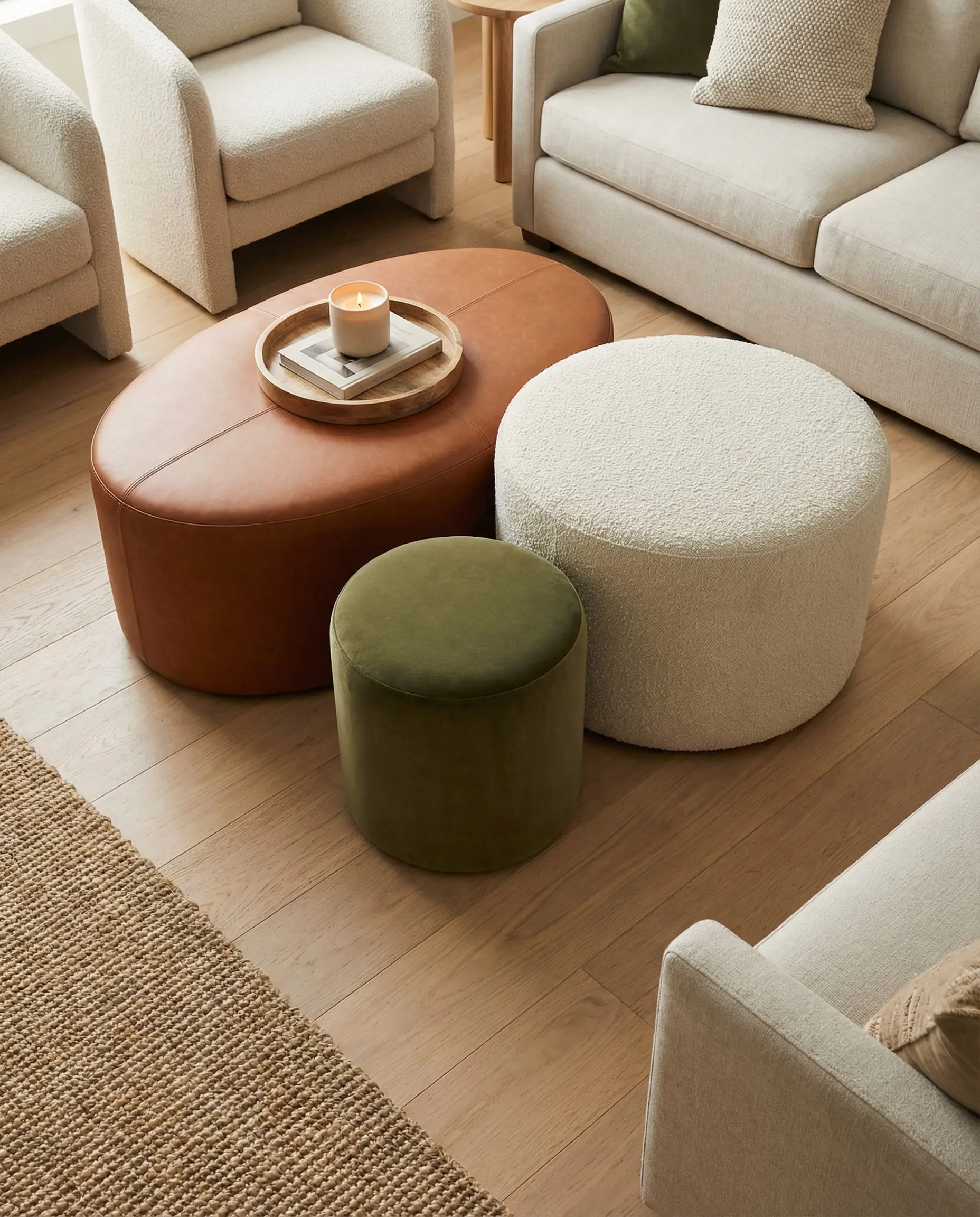Cluster of nesting ottomans in leather, velvet, and bouclé used as a coffee table.