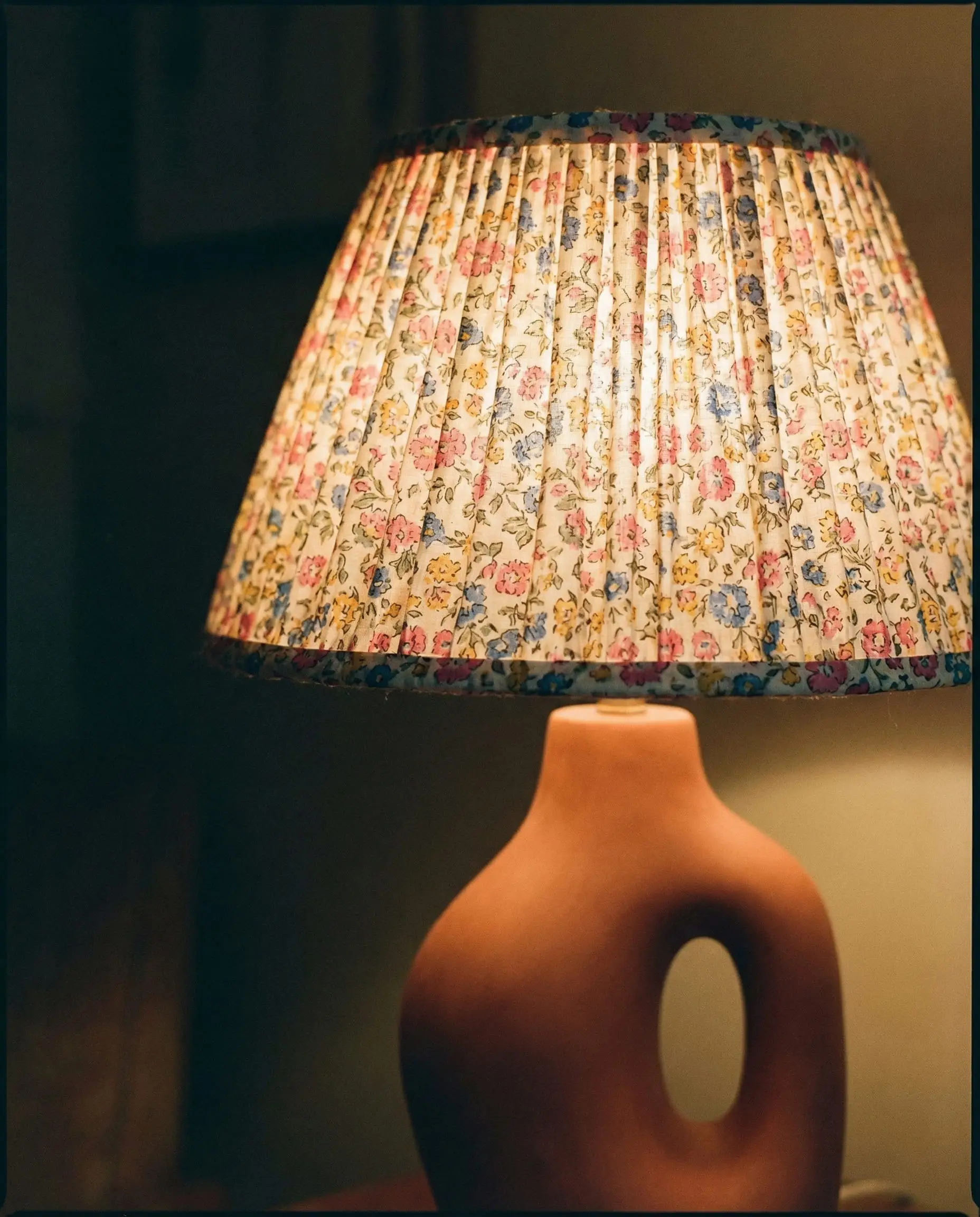 Pleated floral print lampshade on a modern ceramic lamp base.
