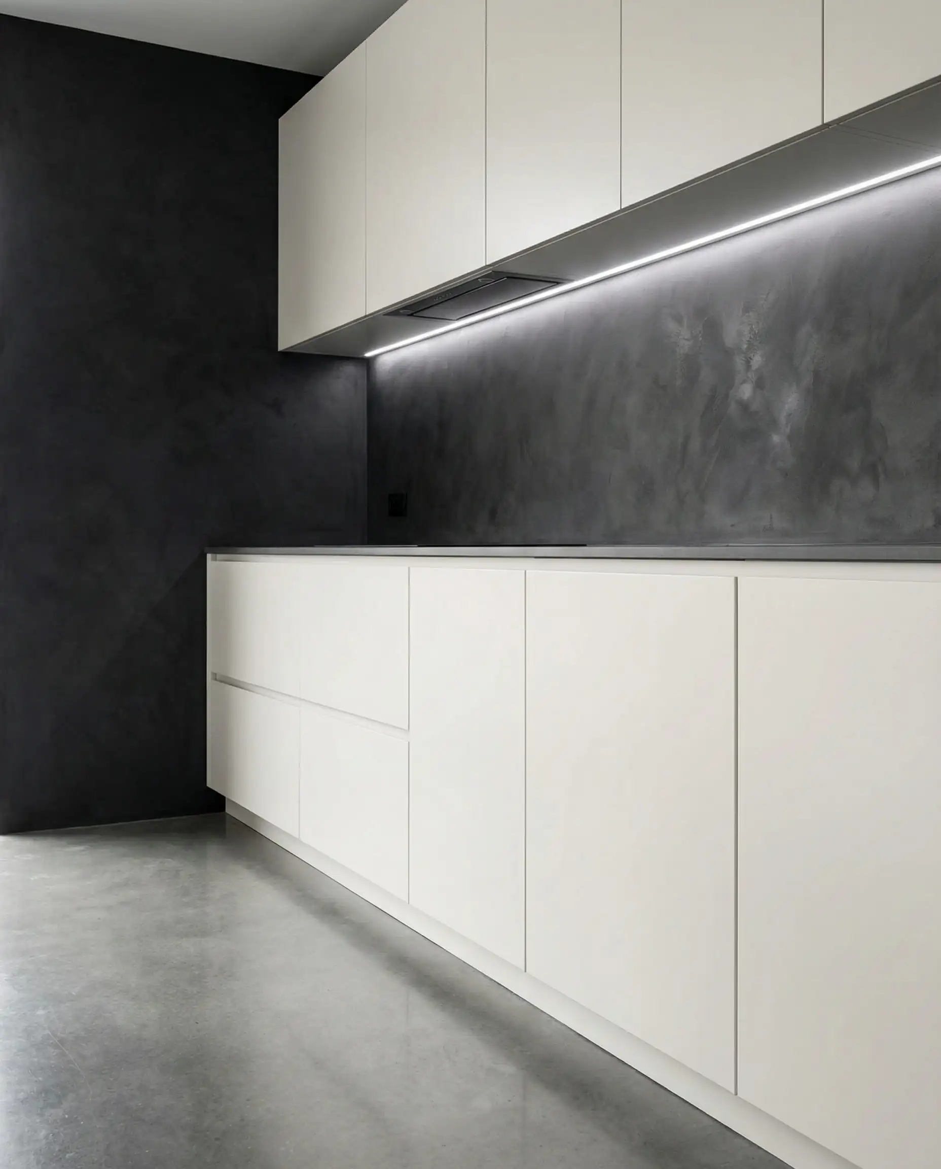 Sleek flat-panel cabinets in Sherwin-Williams Pure White against a dark charcoal limewash wall.