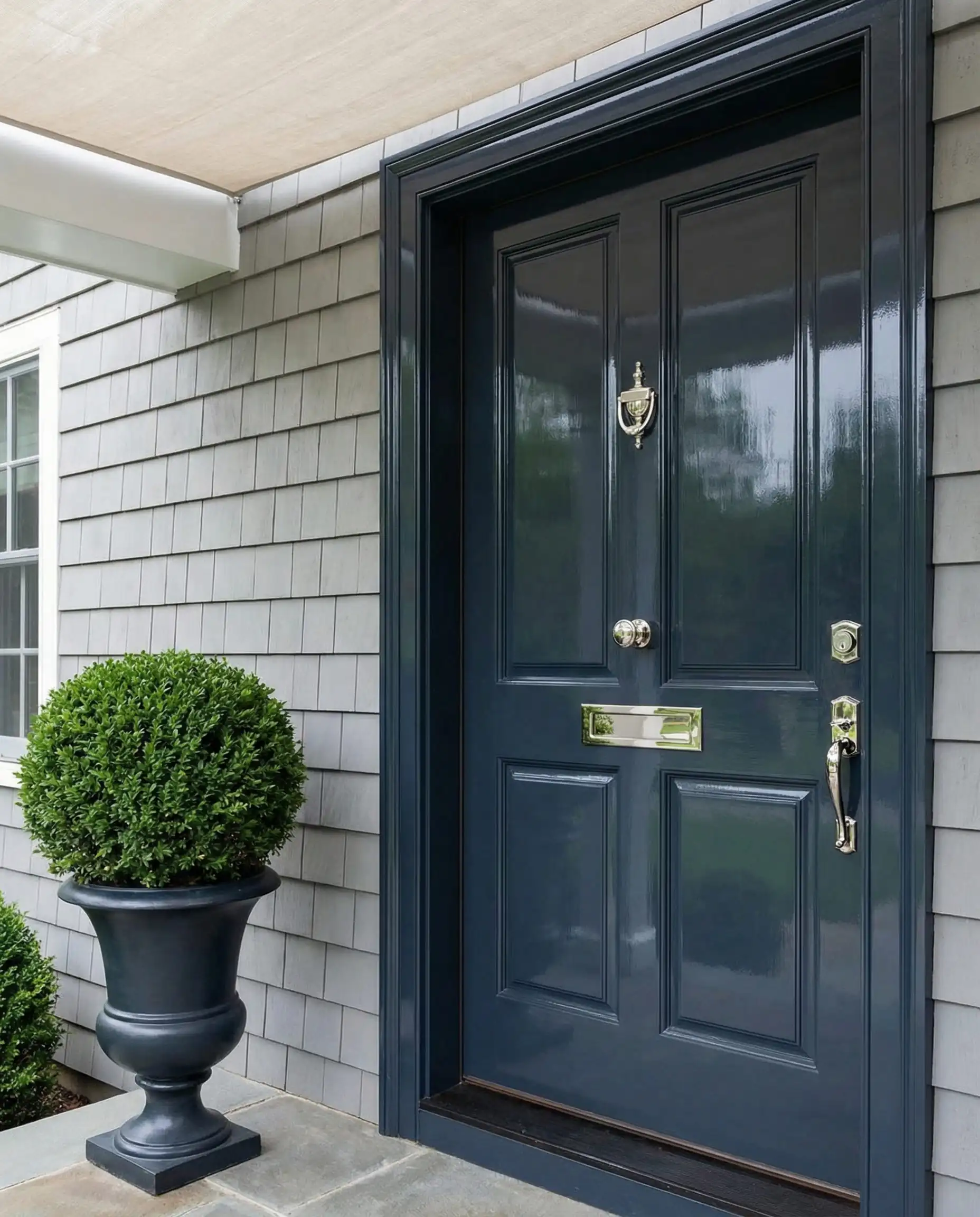 High-gloss front door painted in Sherwin-Williams Naval on a gray shingle house.