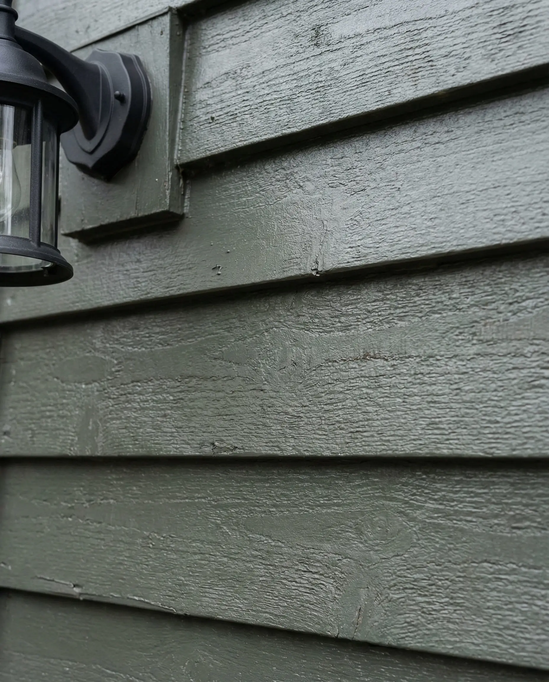 Close-up texture of siding in Sherwin-Williams Pewter Green showing steely undertones.