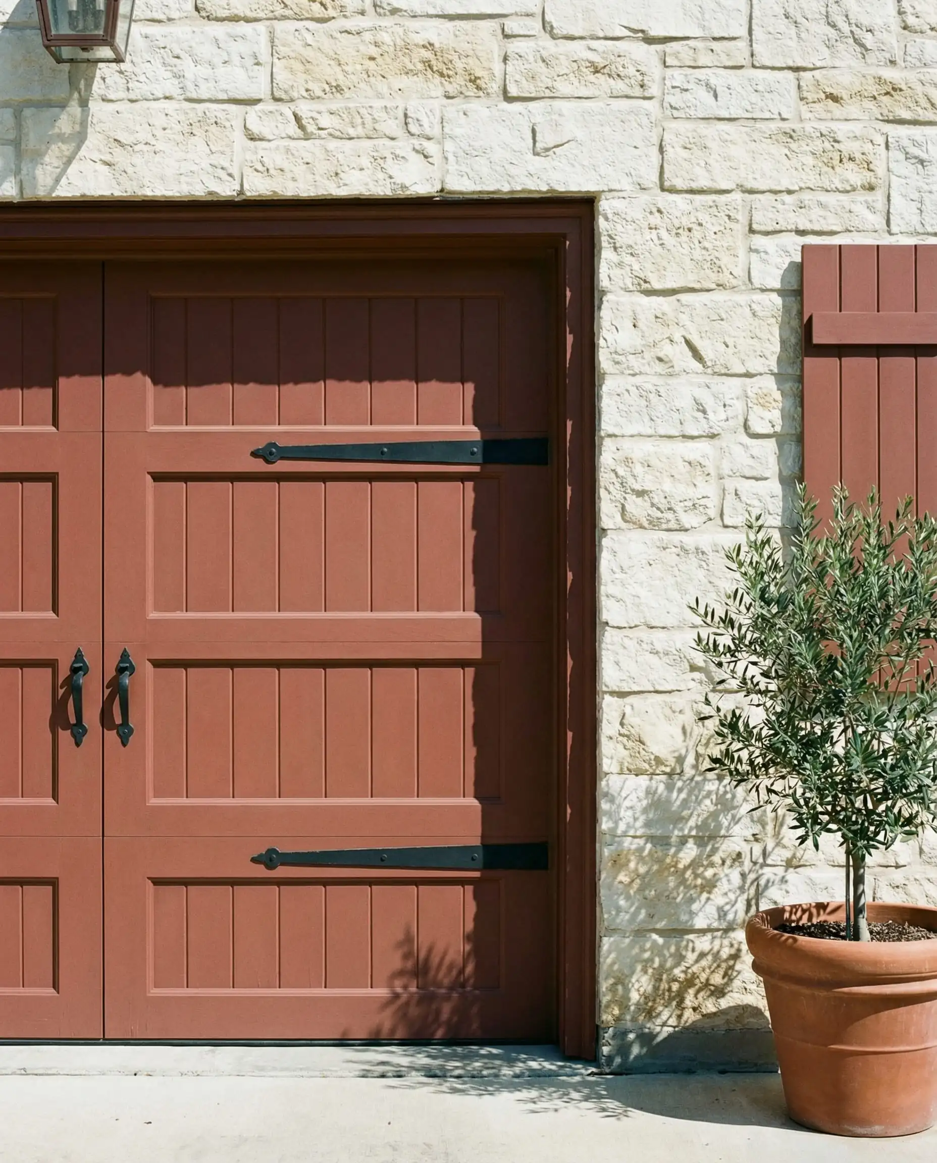 Garage door painted in Sherwin-Williams Reddened Earth contrasting with limestone walls.