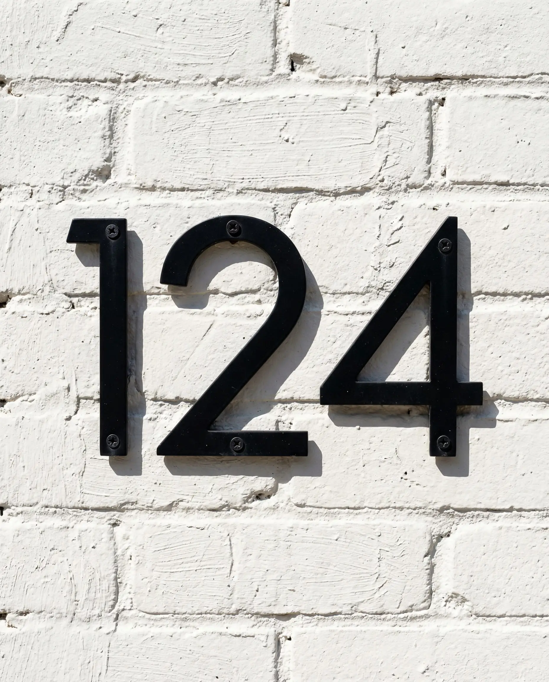 Industrial chic painted brick wall in Sherwin-Williams Snowbound with black numbers.