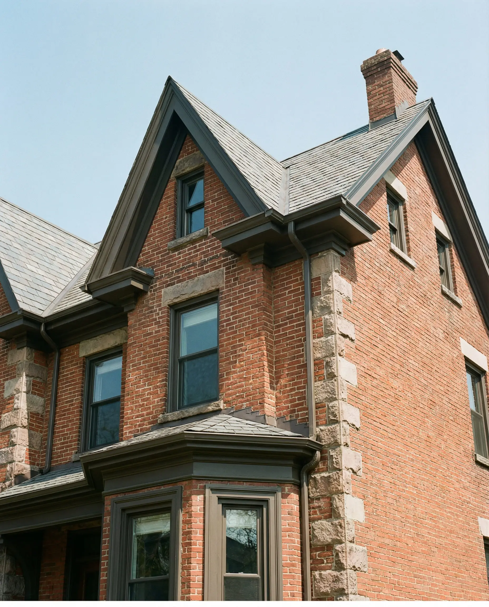 Red brick house featuring Sherwin-Williams Urbane Bronze on fascia and window trim.